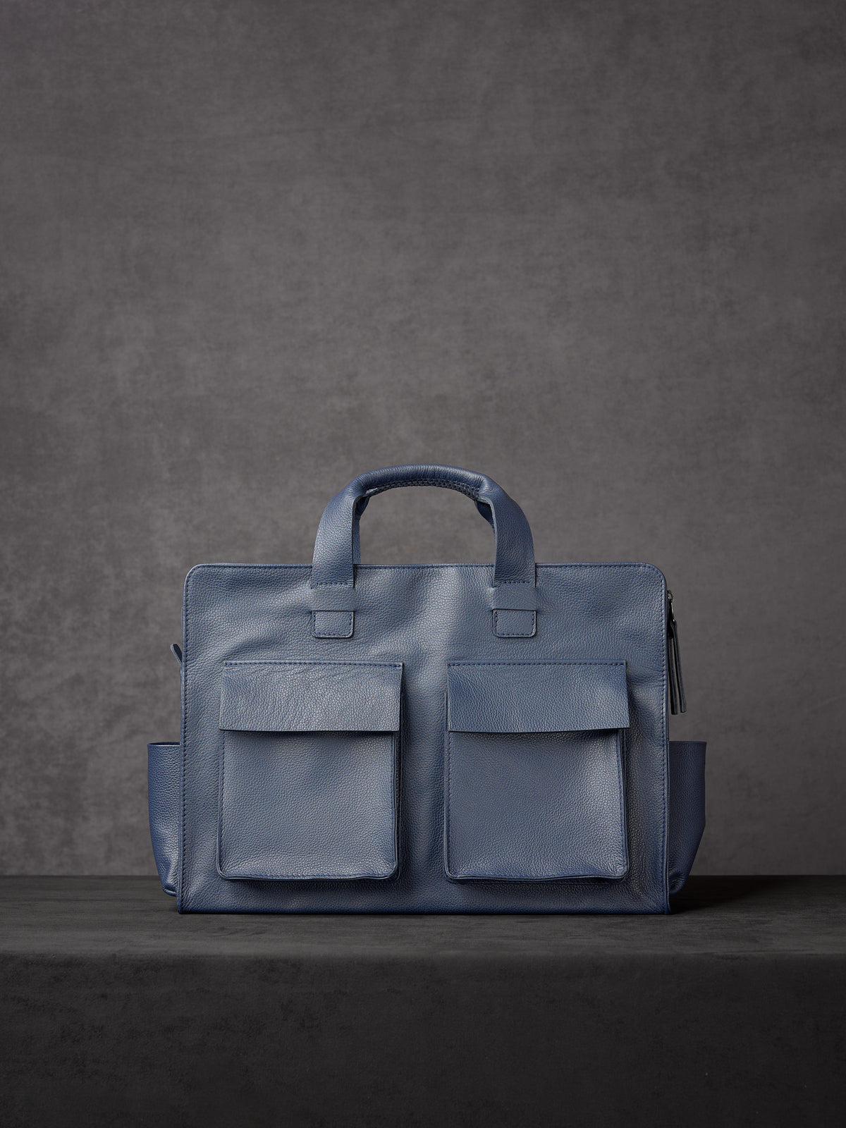 Rear view of Capra Leather blue leather briefcase featuring two large symmetrical exterior flap pockets.