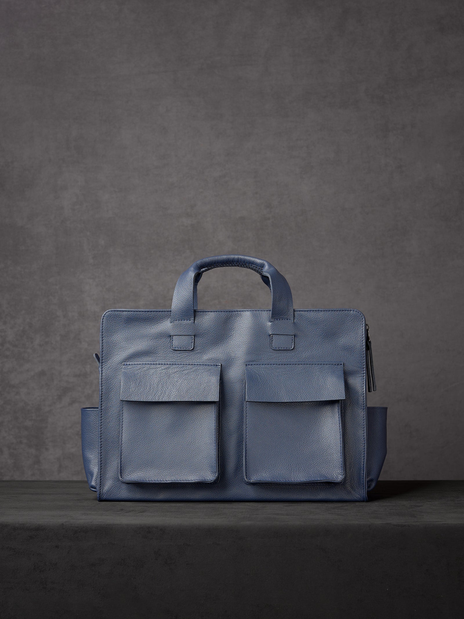 Rear view of Capra Leather blue leather briefcase featuring two large symmetrical exterior flap pockets.