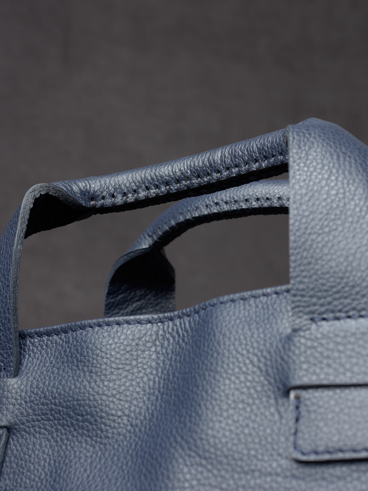 Close-up of the heavy-duty stitching on Capra Leather navy briefcase handles.