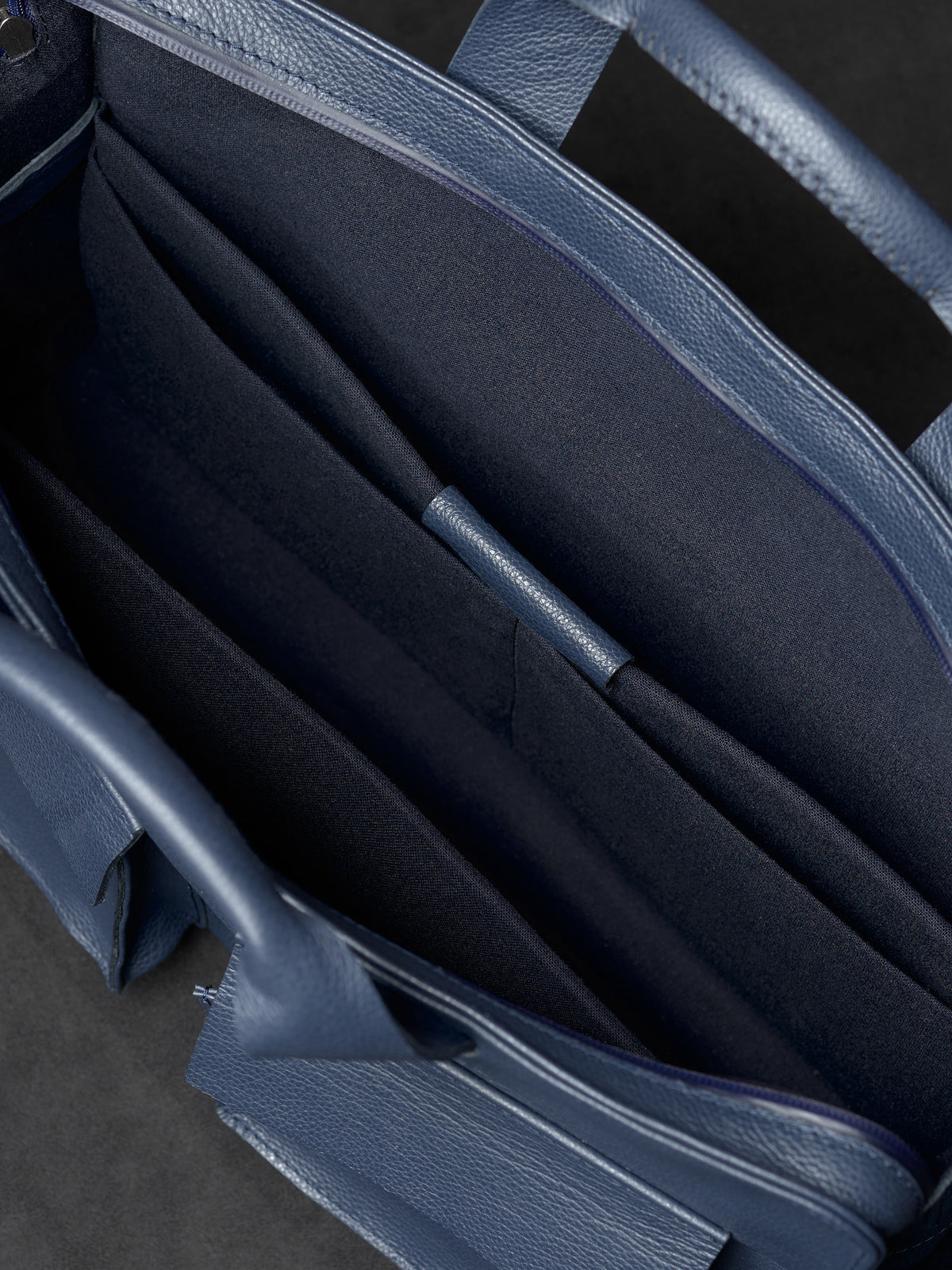 Empty main compartment and storage pockets inside Capra Leather navy leather bag.