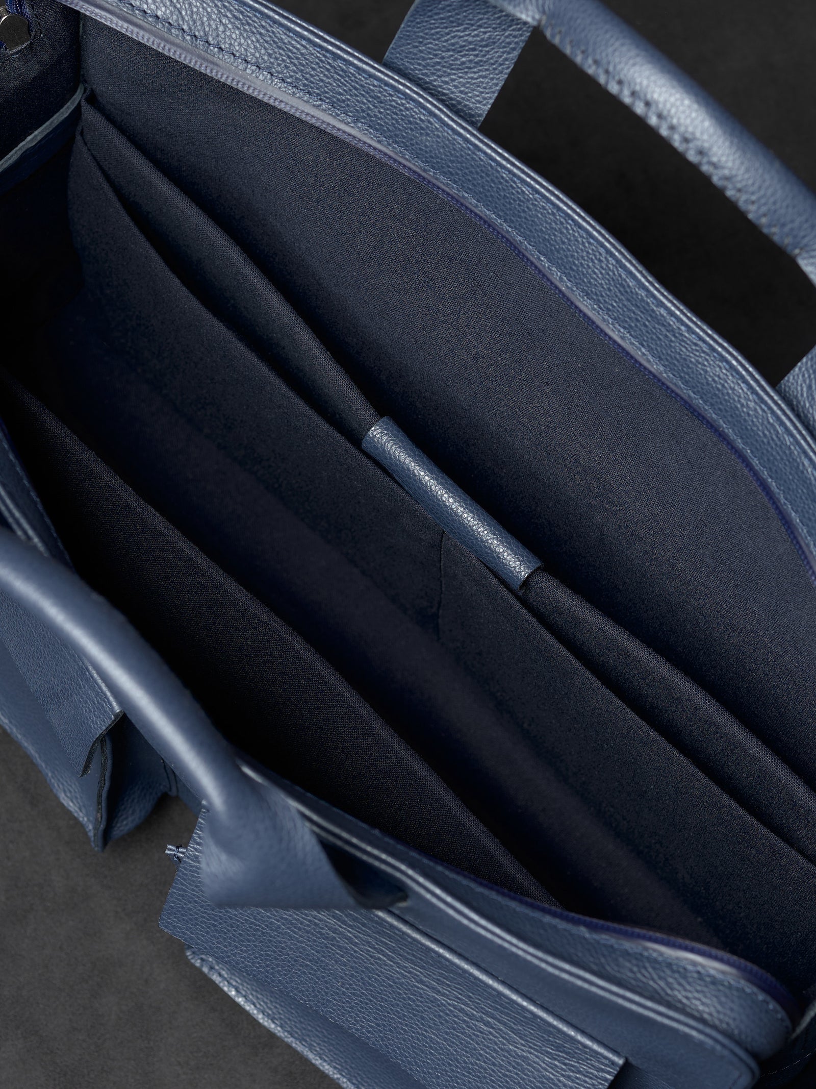 Empty main compartment and storage pockets inside Capra Leather navy leather bag.
