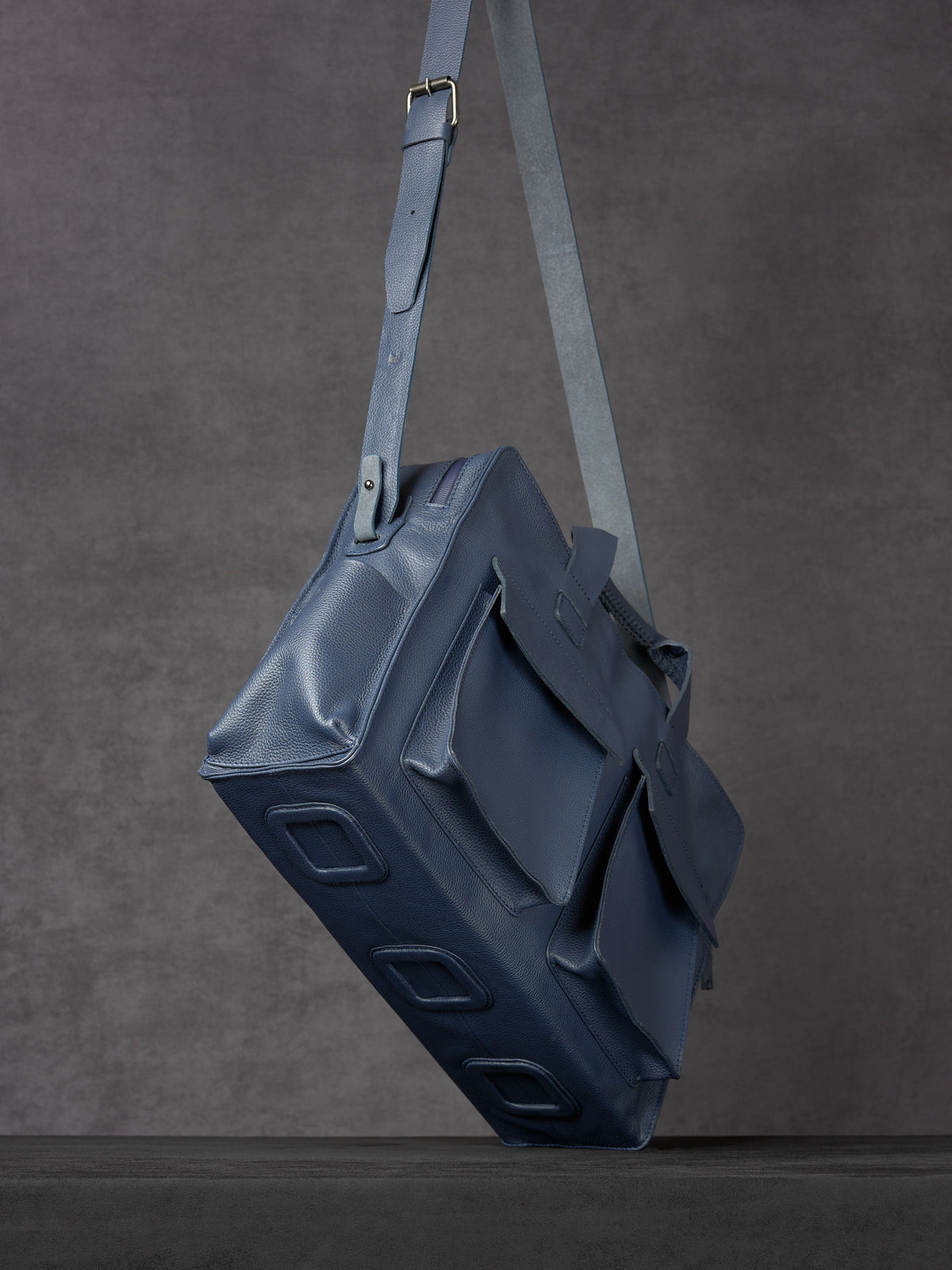 Floating view of Capra Leather navy leather messenger bag showing bottom panels.