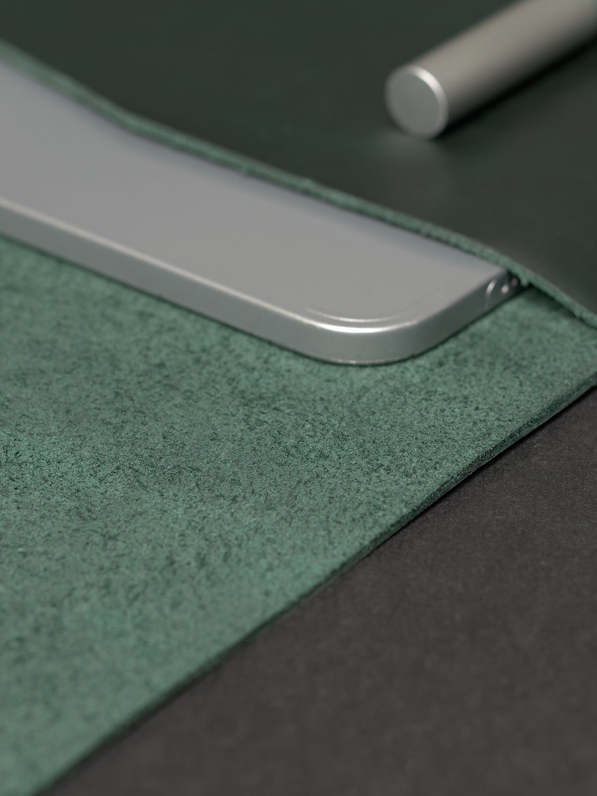 Close-up texture shot showing the rough green suede interior and smooth green leather exterior with a silver device.