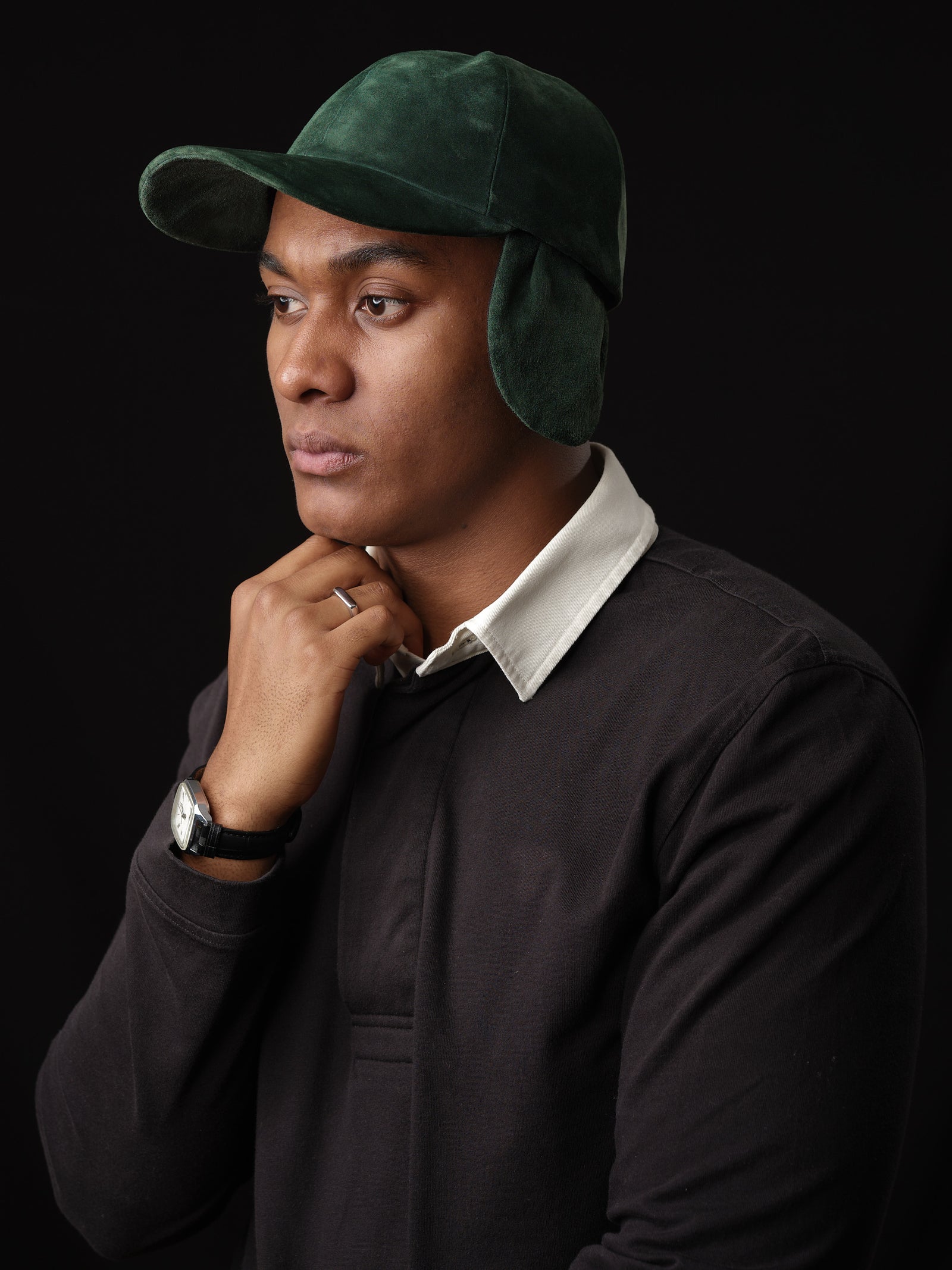 Man wearing a green suede baseball cap with ear flaps, handcrafted by Capra Leather