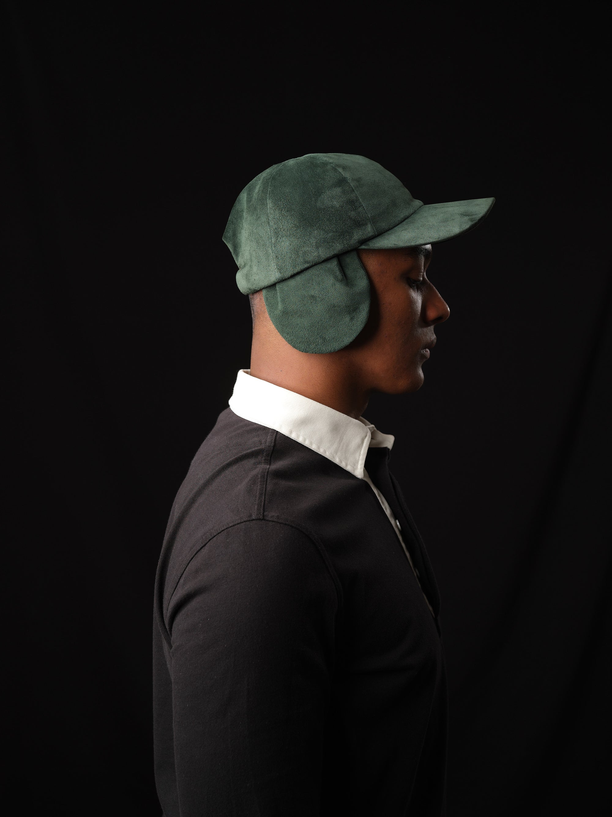 Studio shot of a man in a classic green suede baseball cap with ear flaps 