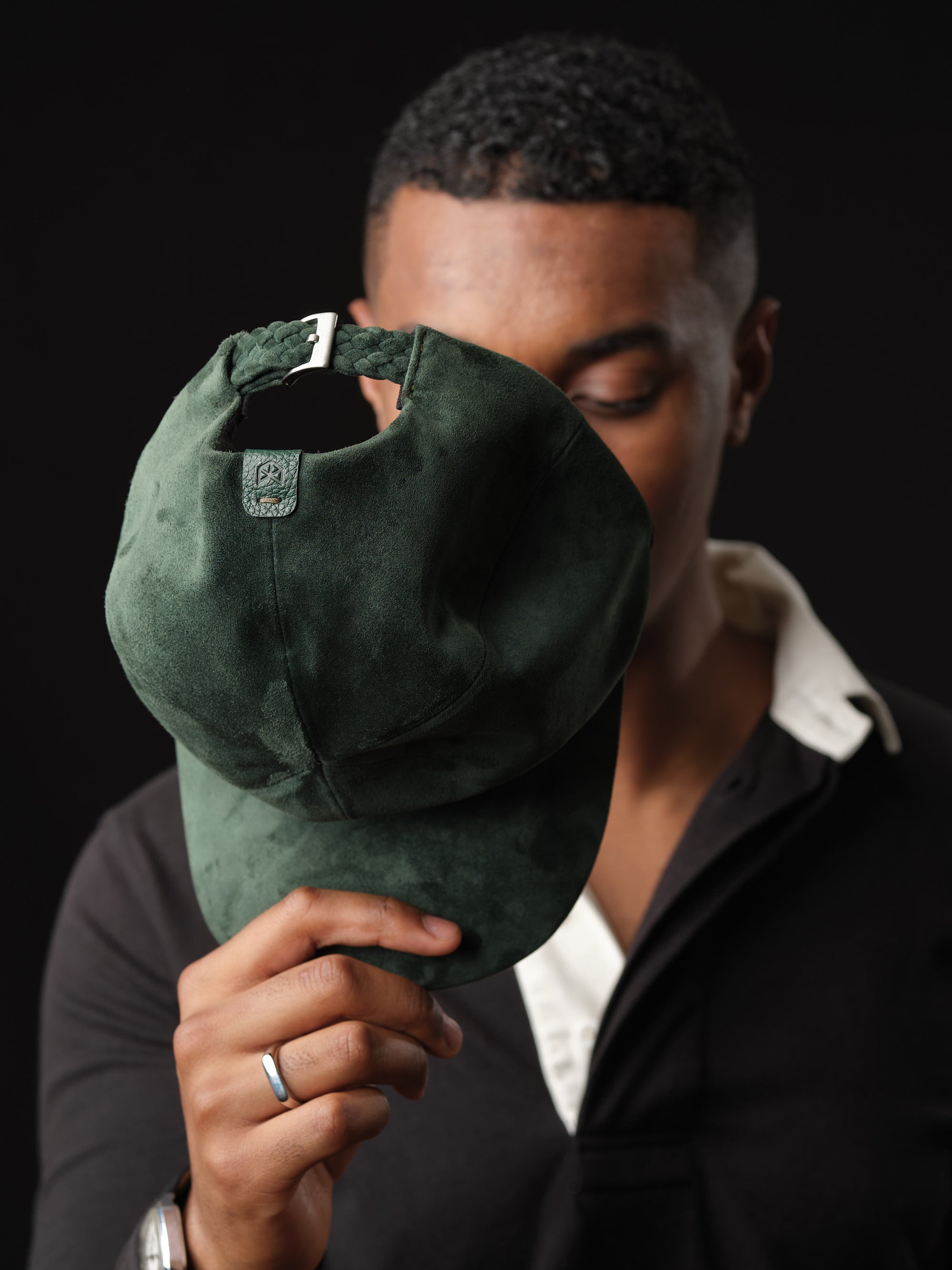 Man posing in a stylish green suede baseball cap, handcrafted by Capra Leather 