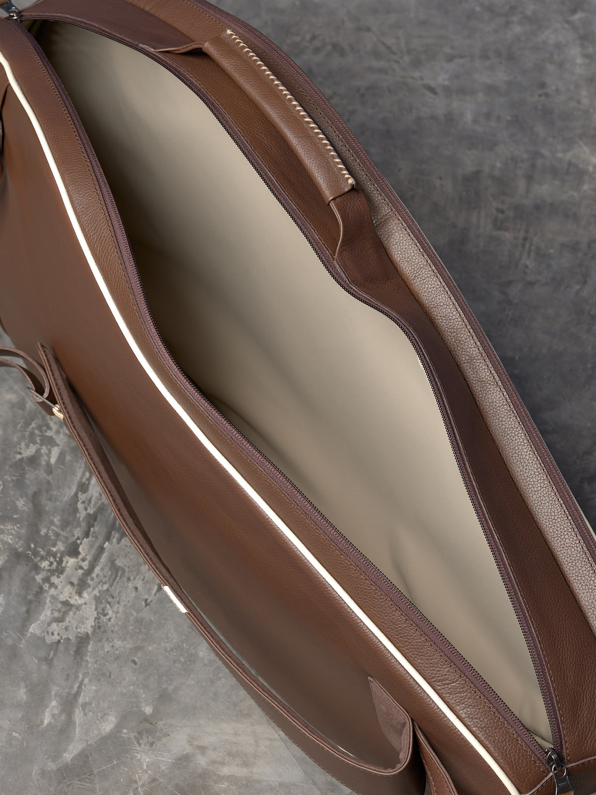 Top-down view of an open leather tennis bag showing a spacious main compartment with a light-colored interior lining.
