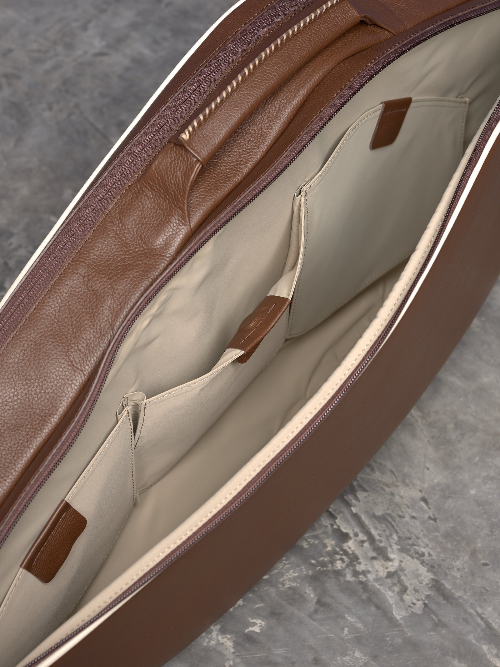 Detailed view of the interior pockets of a leather tennis bag, featuring specialized compartments for organization.