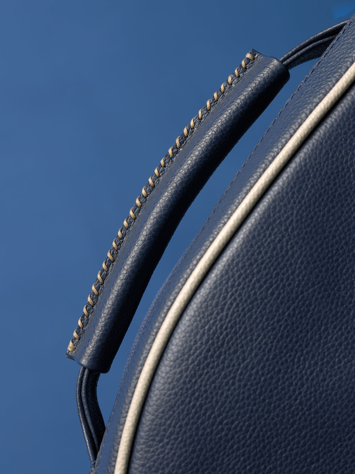 Close-up of the rolled leather top handle, featuring contrast stitching and texture.