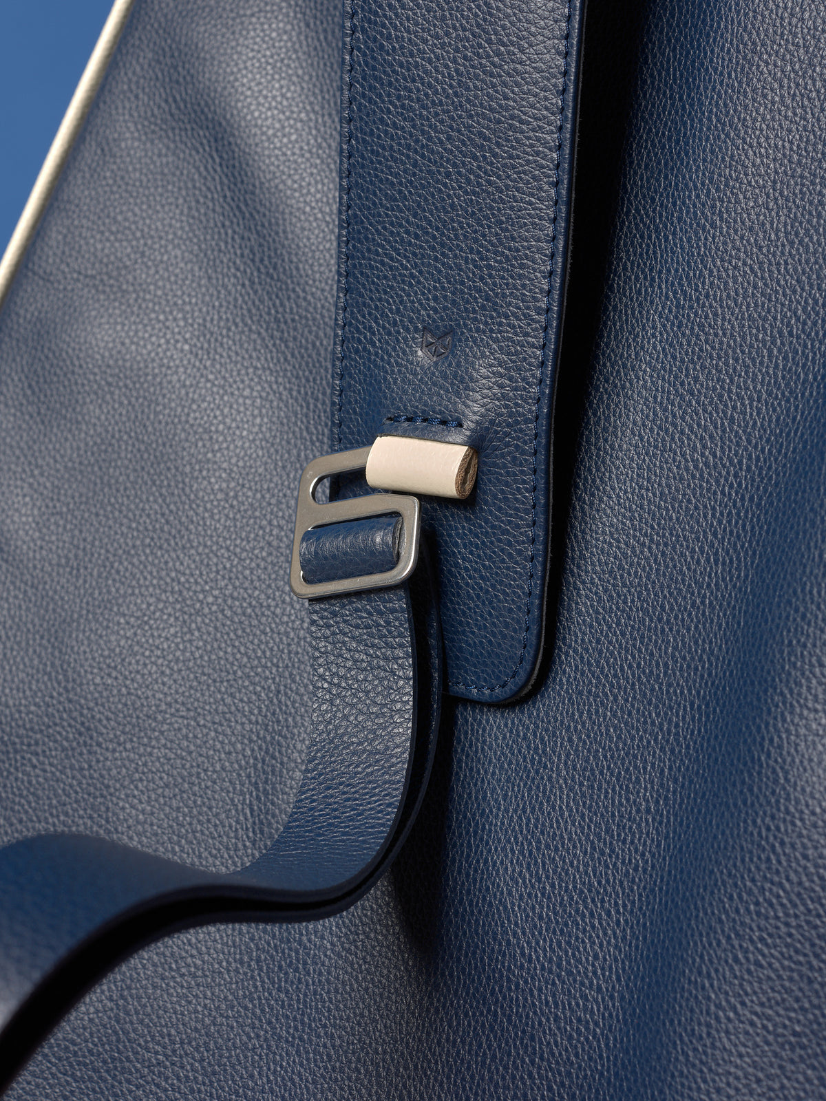 High-definition shot of the metal adjustment hardware on the wide leather strap of the navy tennis bag.