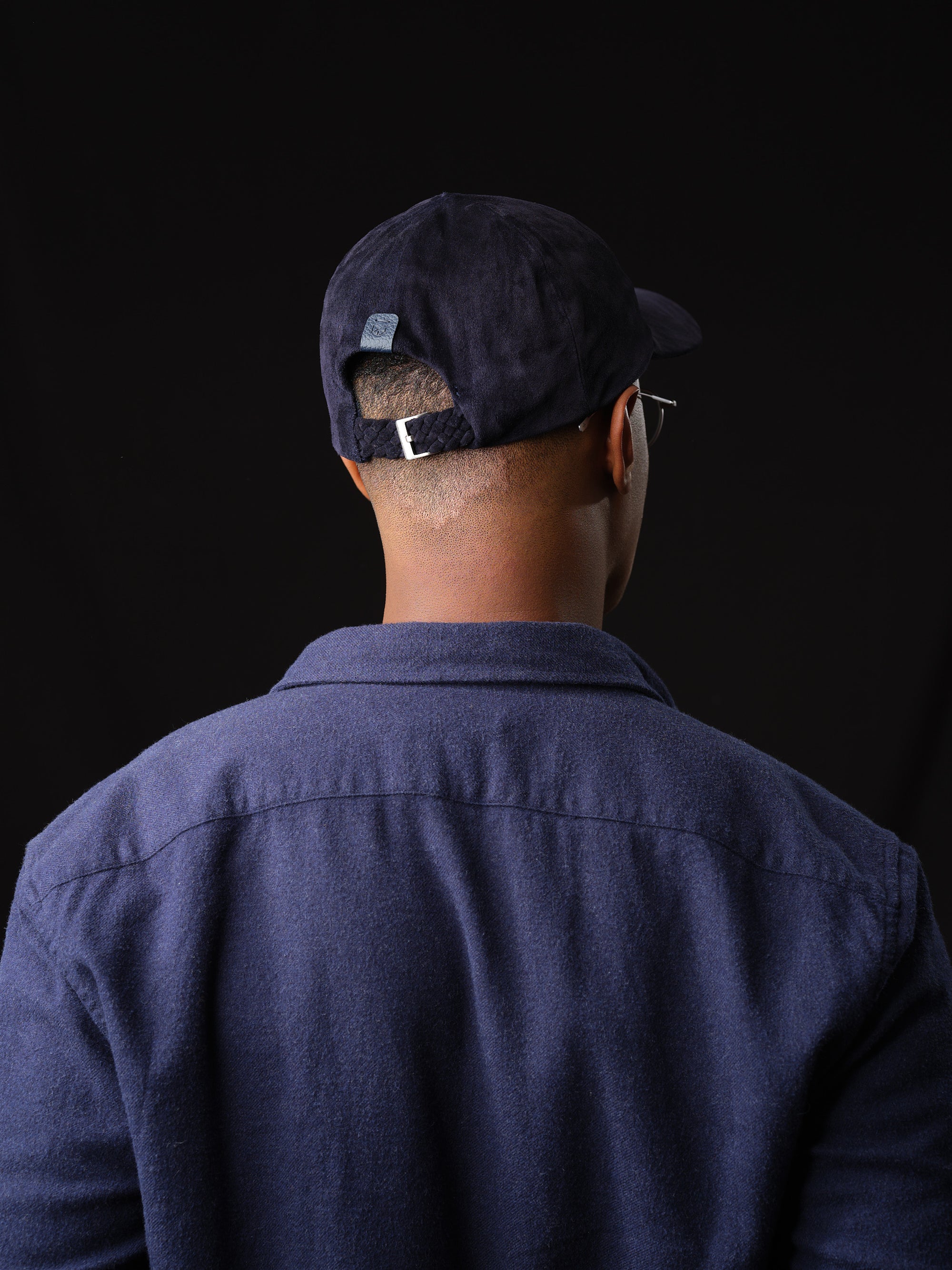 Man wearing a navy suede baseball cap, handcrafted by Capra Leather