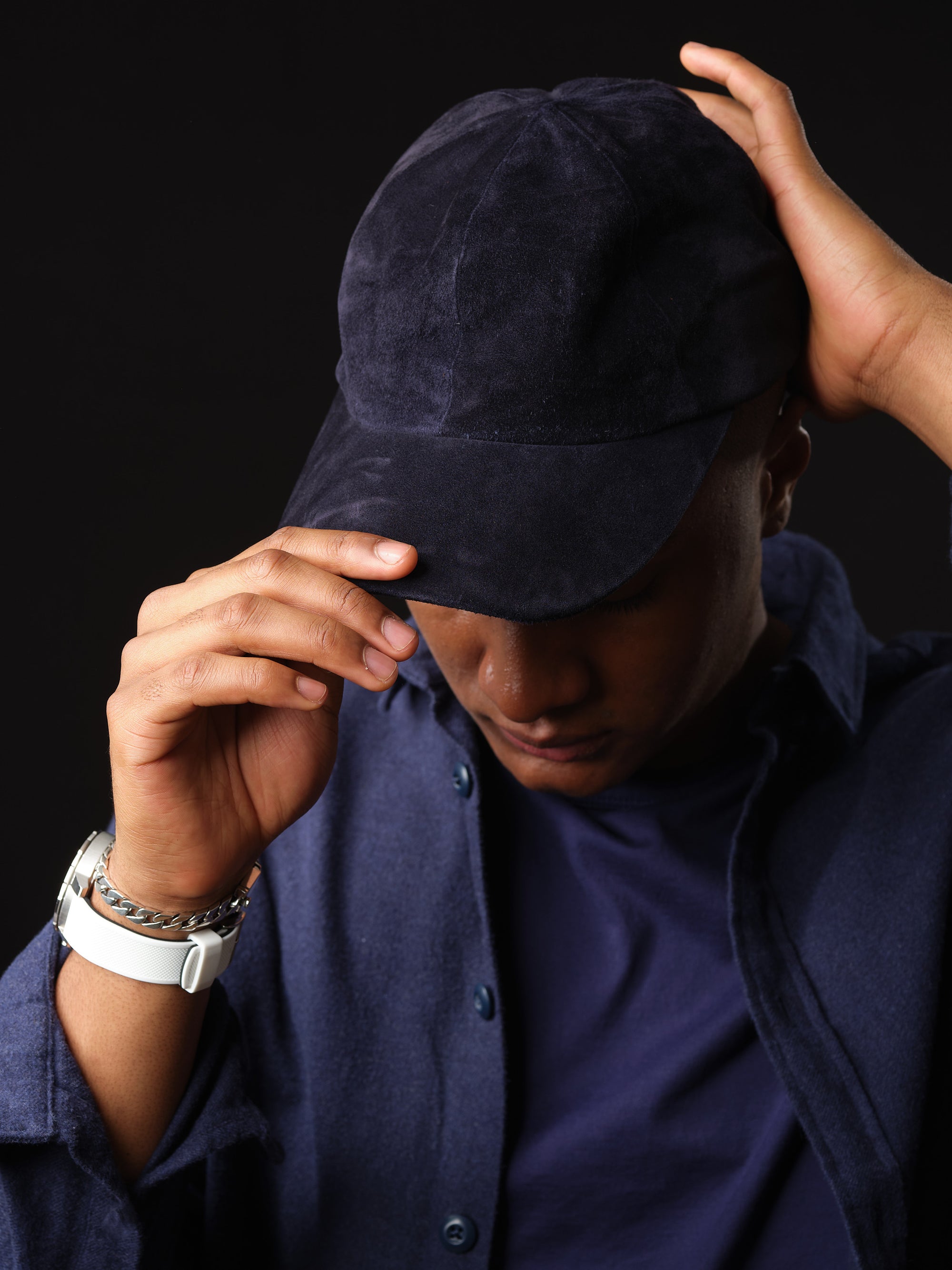 Man wearing a navy suede baseball cap with ear flaps, handcrafted by Capra Leather