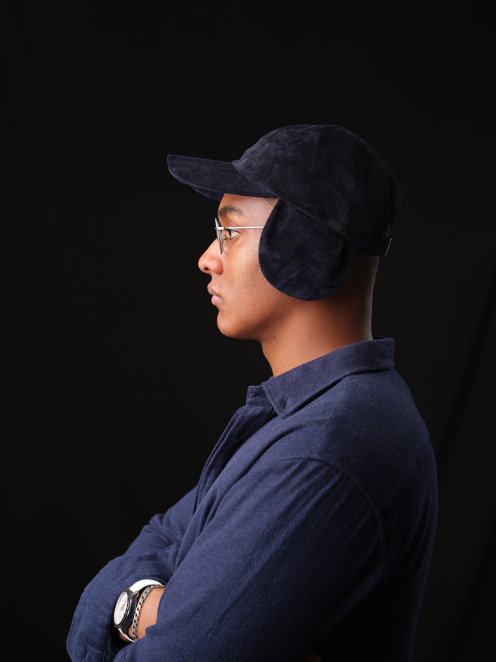 Close-up of a navy suede baseball cap with ear flaps, handcrafted by Capra Leather