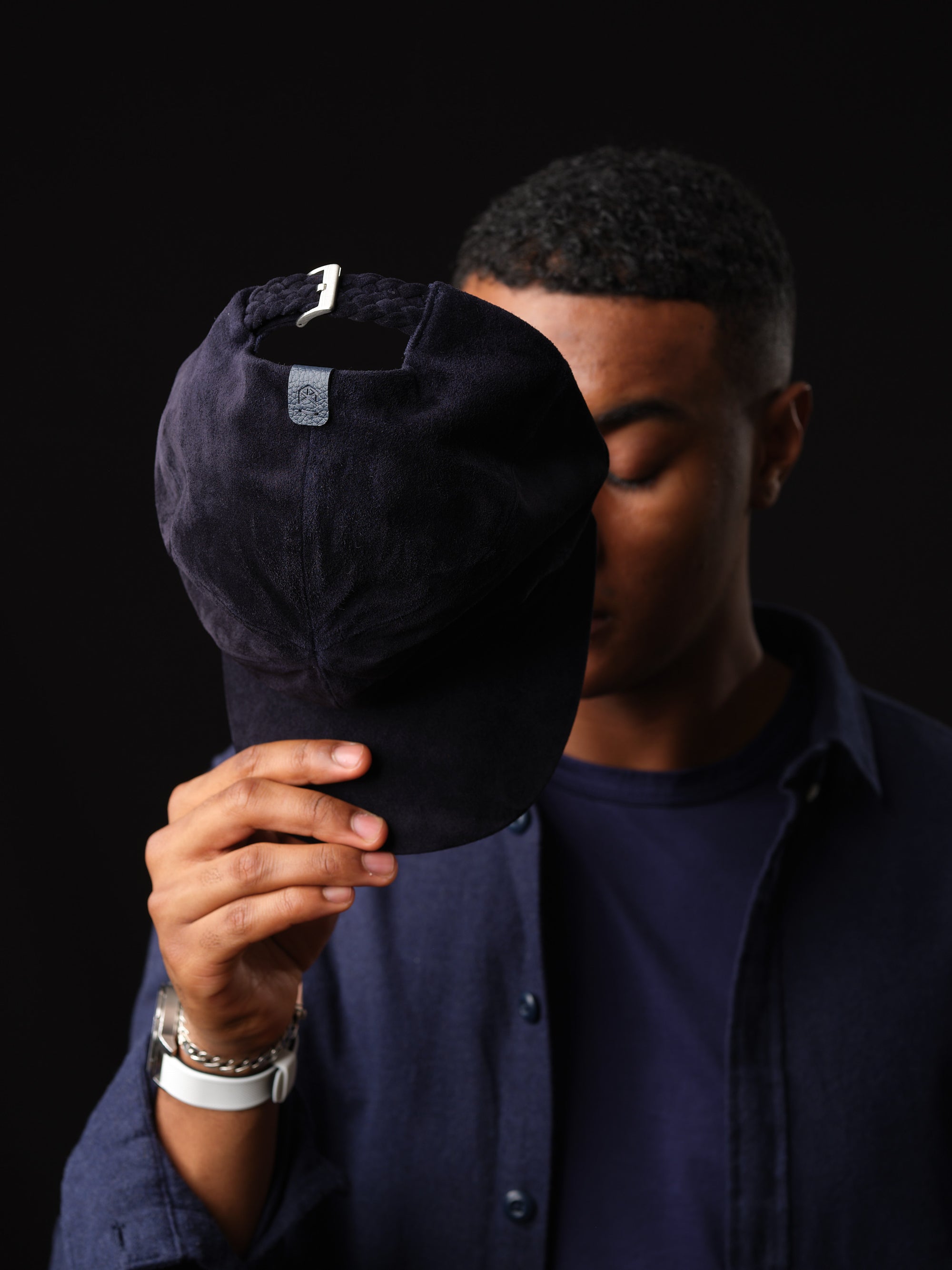 Man posing in a stylish navy suede baseball cap, handcrafted by Capra Leather