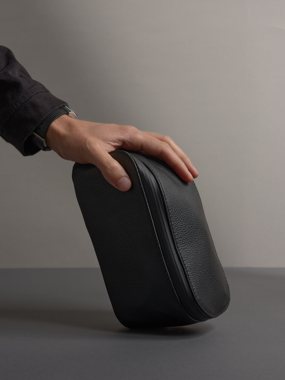 Hand holding the black scout toiletry by Capra Leather