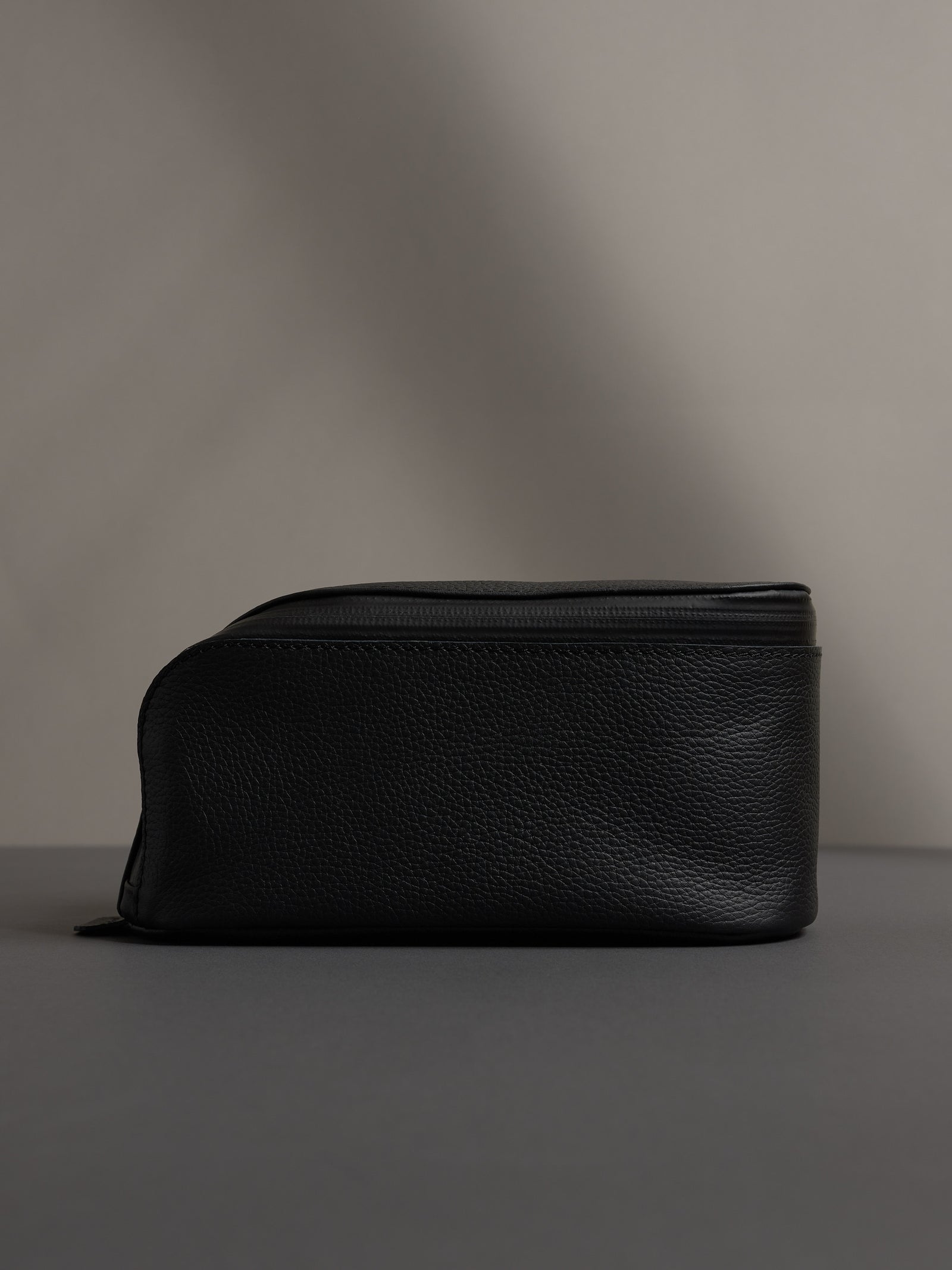Full-side profile view of the black leather dopp kit, showcasing its capacity and structured shape.