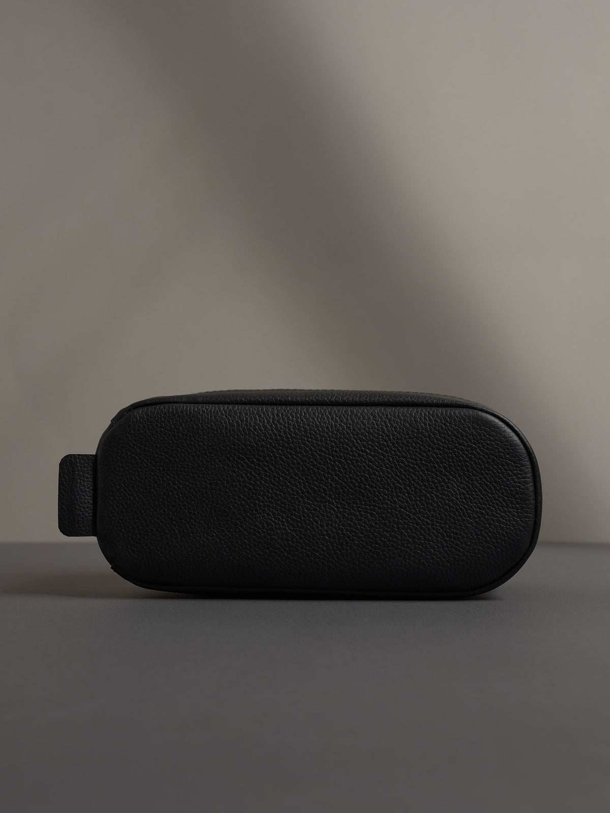 Bottom view of the black leather dopp kit, showing its sturdy, flat base for stability.