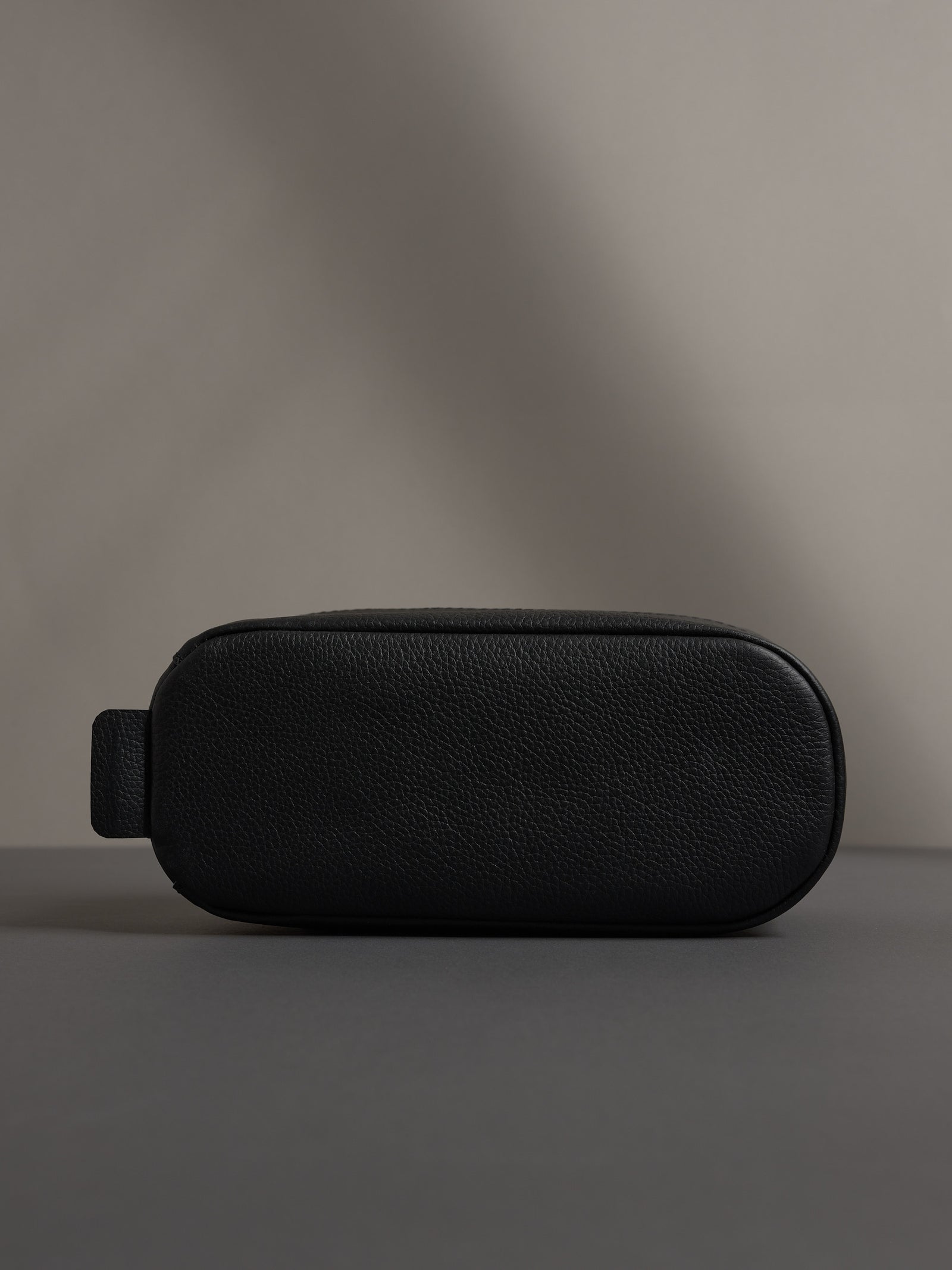 Bottom view of the black leather dopp kit, showing its sturdy, flat base for stability.