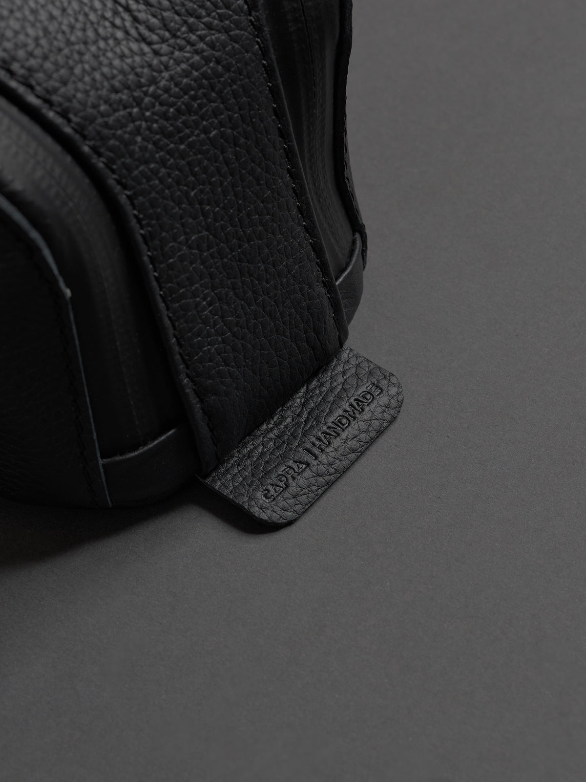 Close-up of the pebbled leather texture and the embossed "CAPRA HANDMADE" tag on the side.