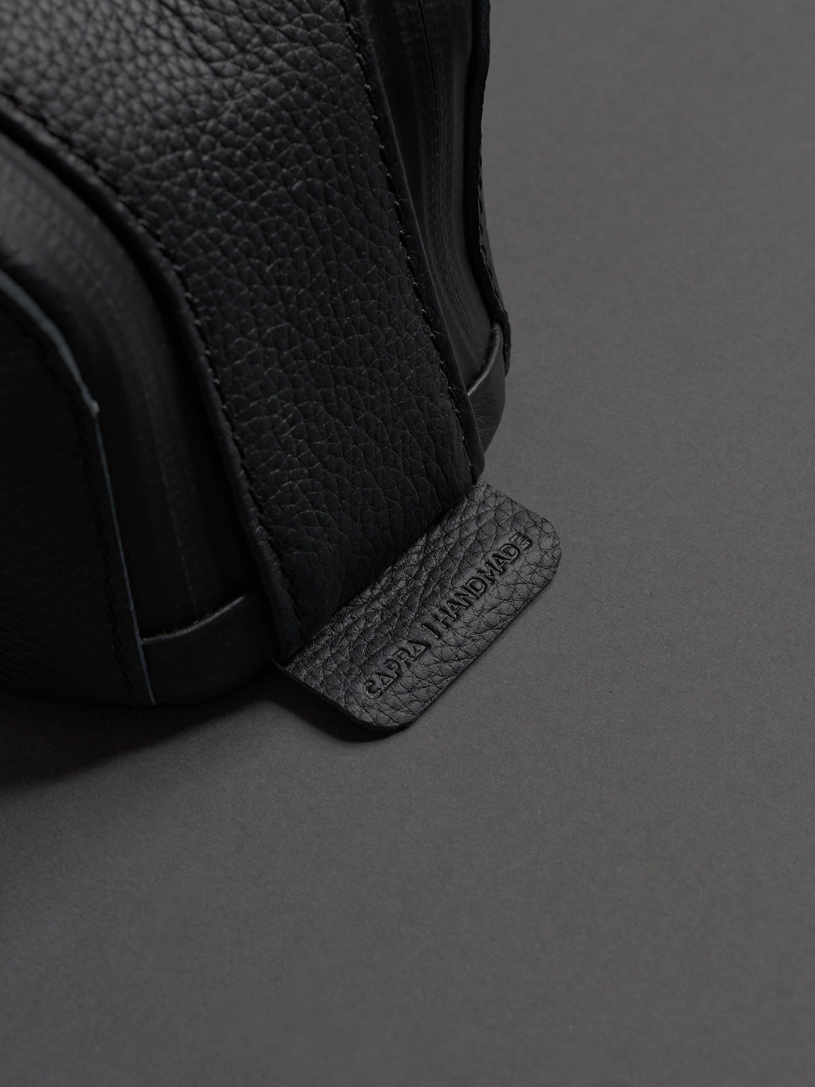 Close-up of the pebbled leather texture and the embossed "CAPRA HANDMADE" tag on the side.