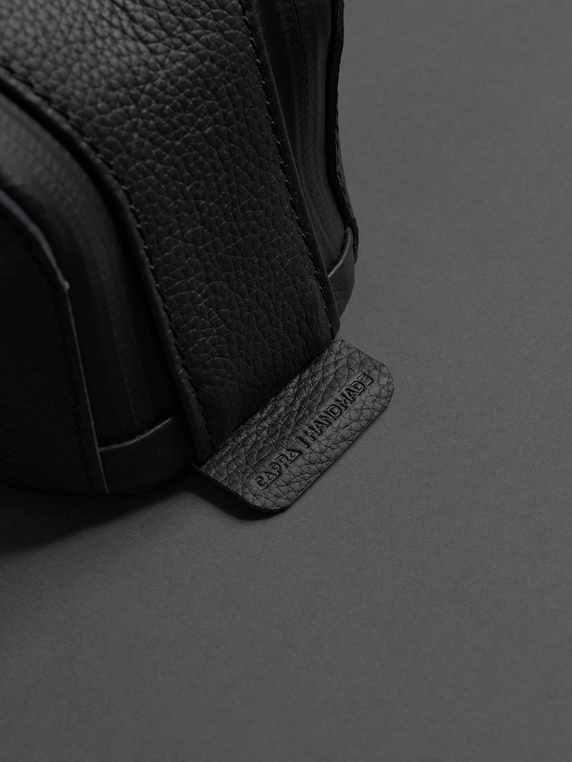 Close-up of the pebbled leather texture and the embossed "CAPRA HANDMADE" tag on the side.
