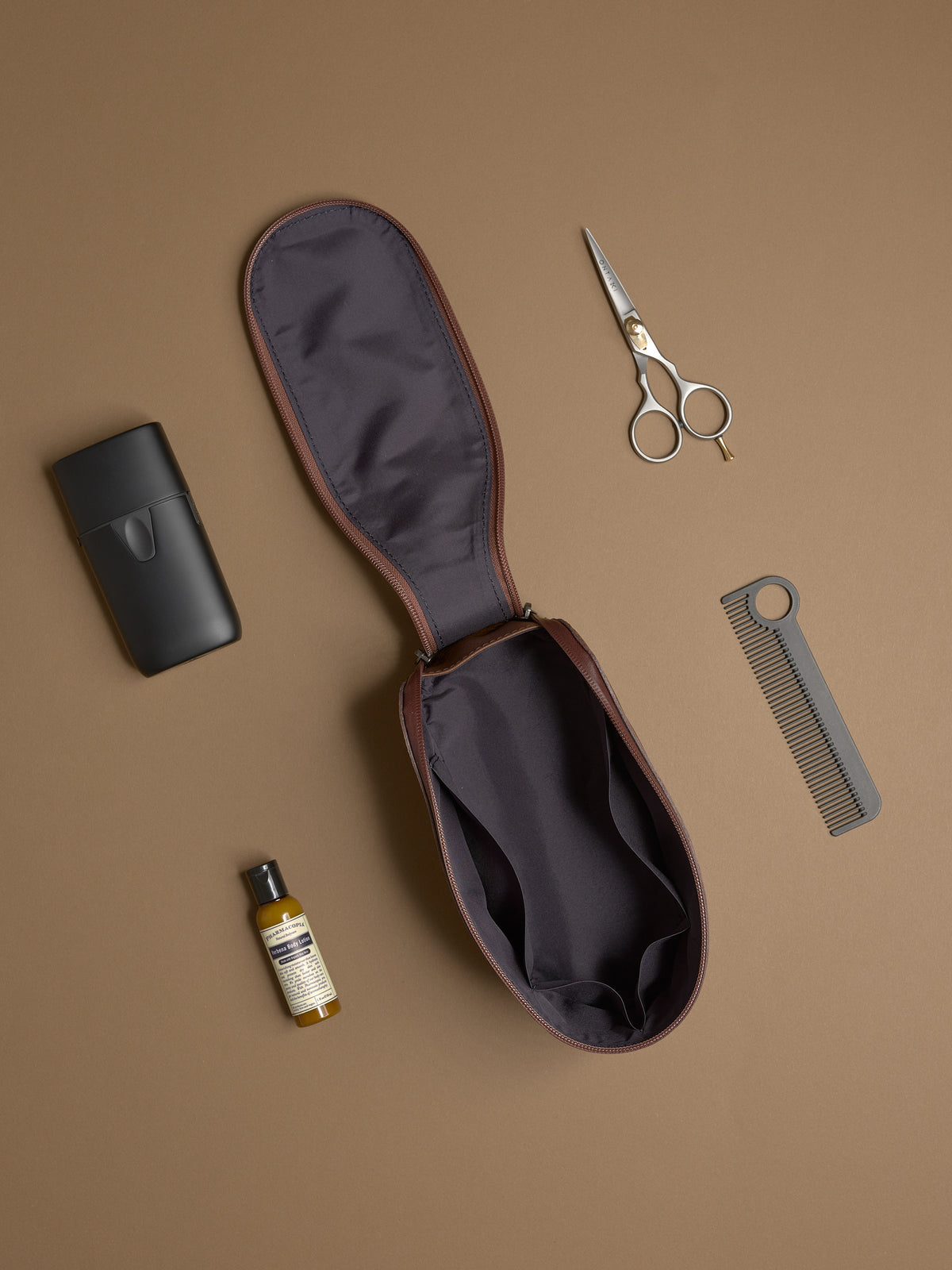 Open brown Capra Leather Toiletry Bag laid flat with scissors, comb, and grooming products.