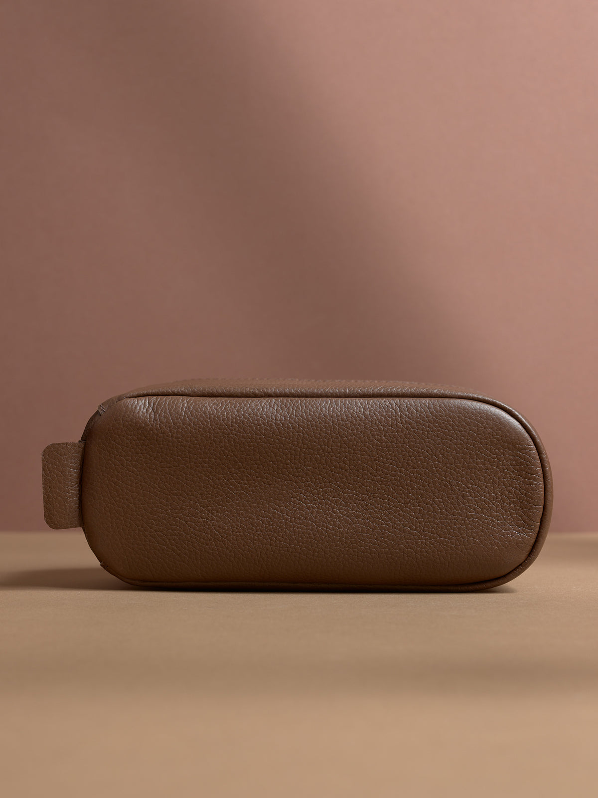 Bottom view of the tan Capra Leather Toiletry Bag with its rounded base and leather loop.
