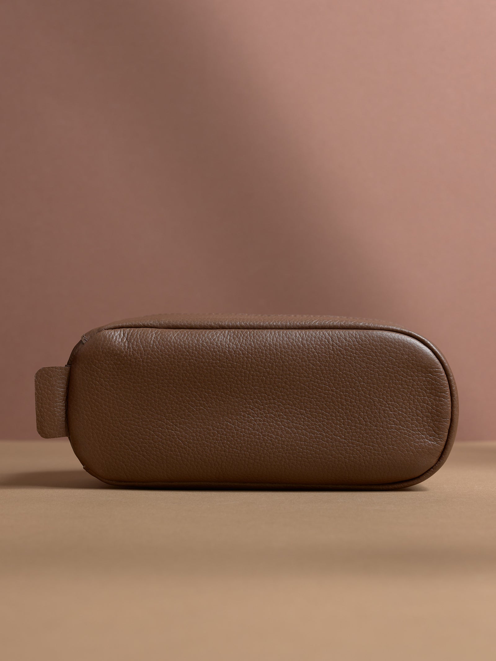 Bottom view of the tan Capra Leather Toiletry Bag with its rounded base and leather loop.