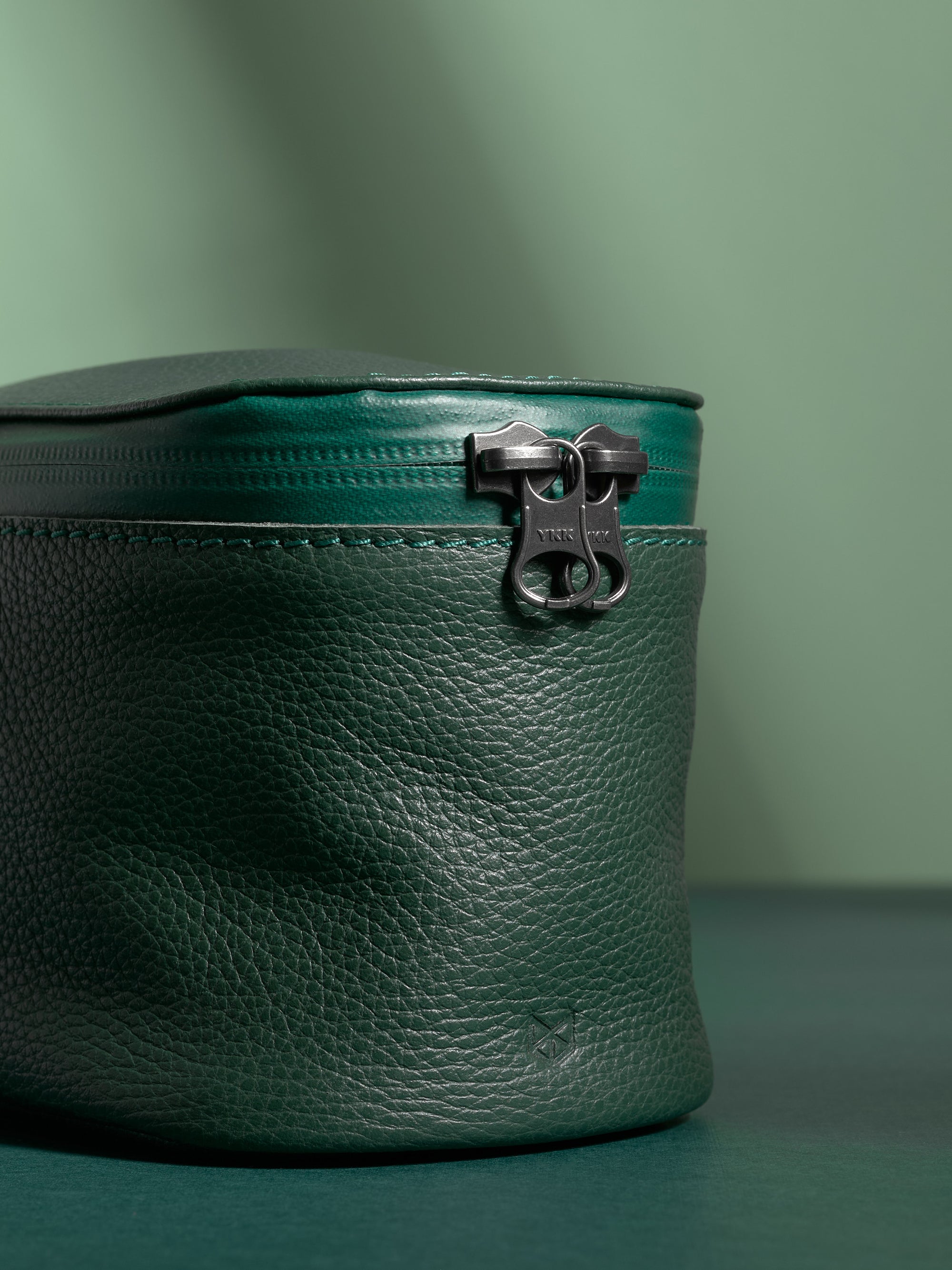 Extreme close-up of the YKK zipper and pebbled texture of the green Capra Leather.