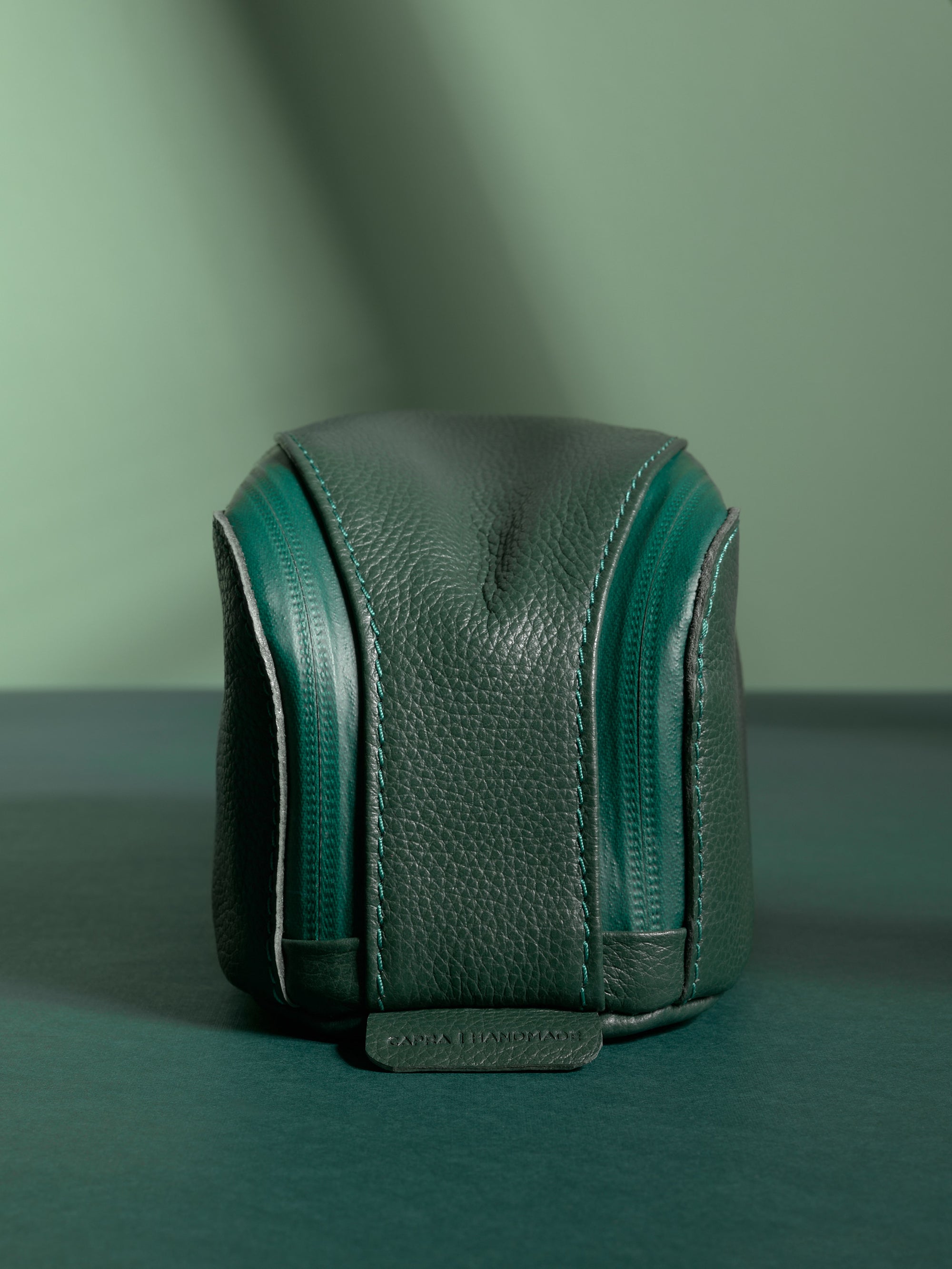 Front view of the vertical green Capra Leather Toiletry Bag highlighting the twin zippers.
