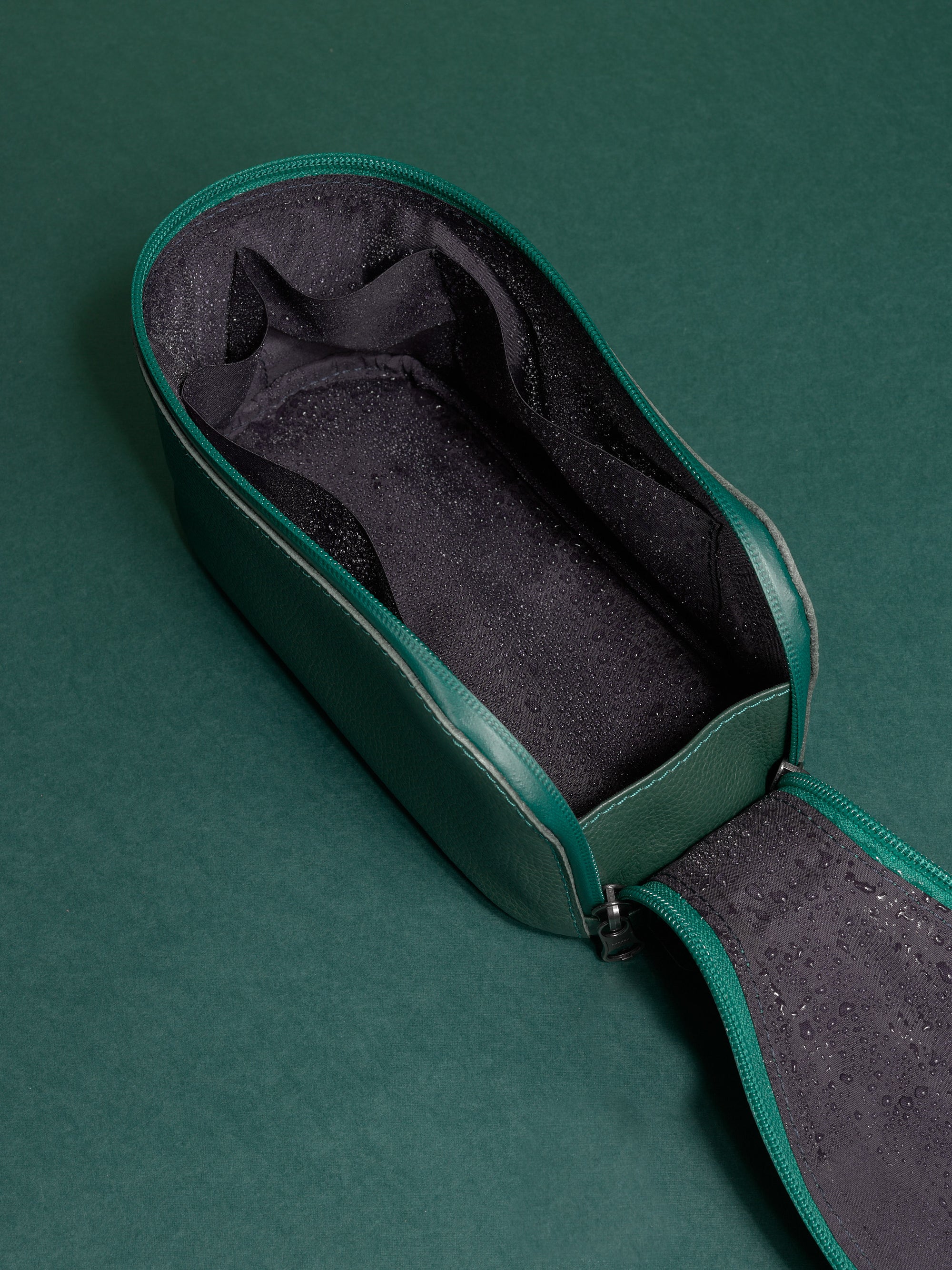 Open green Capra Leather Toiletry Bag interior showing the dark, water-resistant lining with moisture.