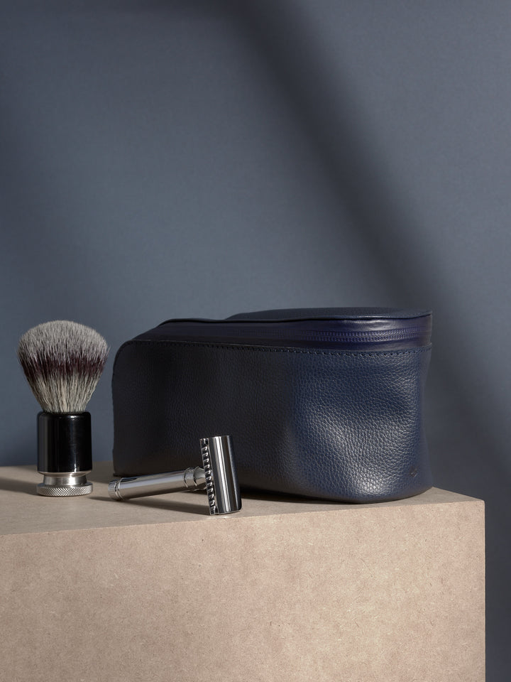 Navy leather toiletry bag with premium shaving tools: safety razor and badger hair shaving brush.