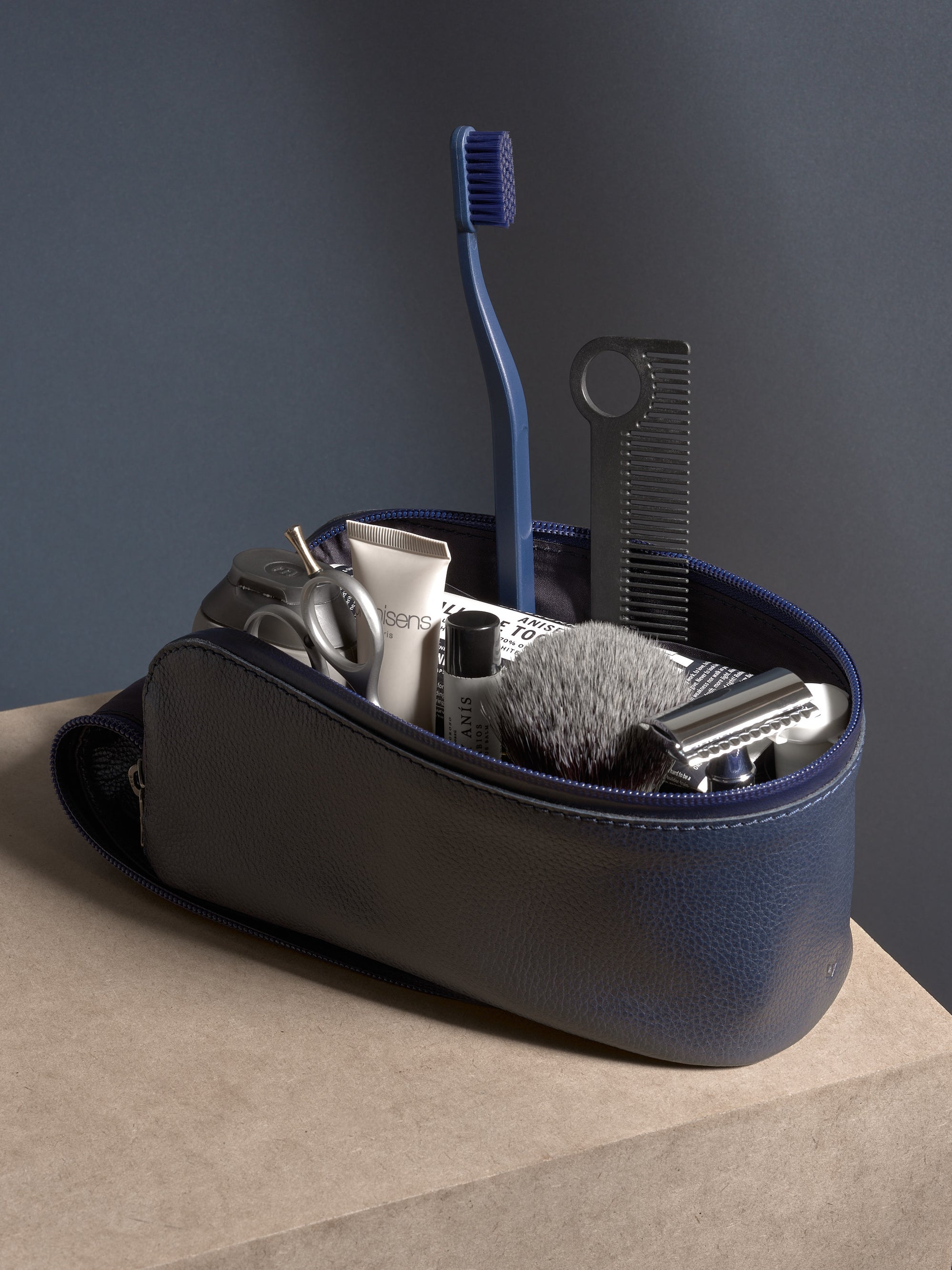 Navy leather toiletry bag with premium shaving tools: safety razor and badger hair shaving brush.