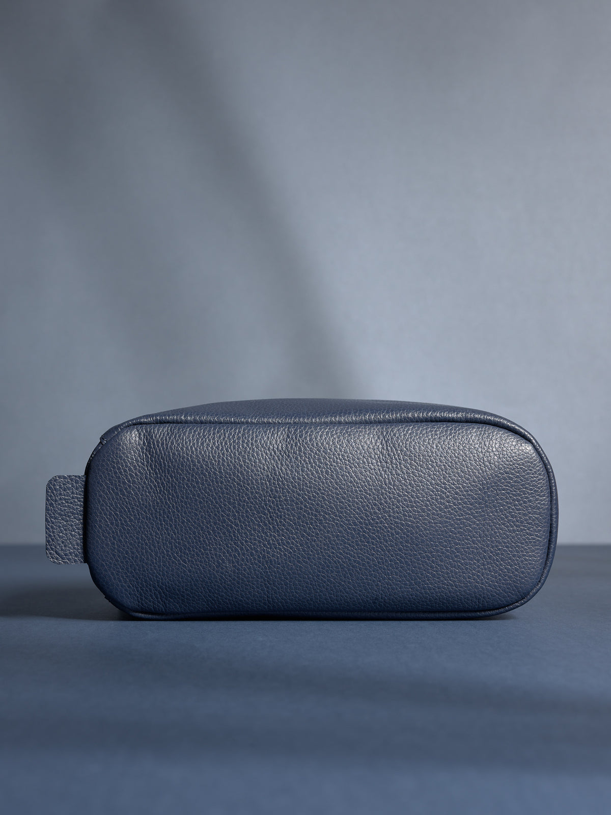 Bottom view of the personalized navy leather toiletry bag, highlighting its durable, flat base.