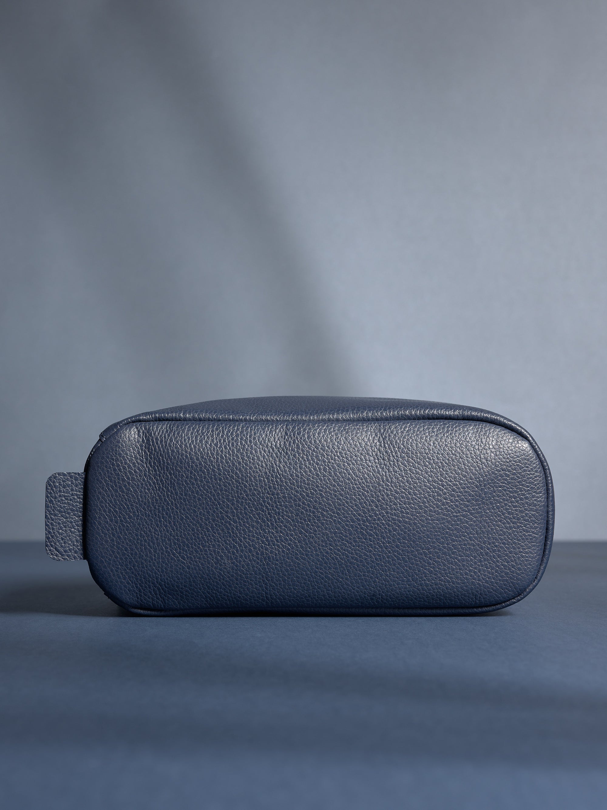 Bottom view of the personalized navy leather toiletry bag, highlighting its durable, flat base.