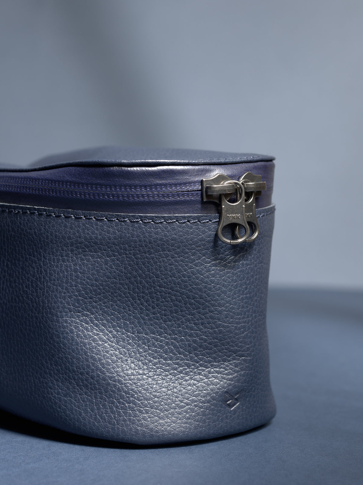 Extreme close-up of the YKK zipper and fine-grain texture of the navy Capra leather dopp kit.