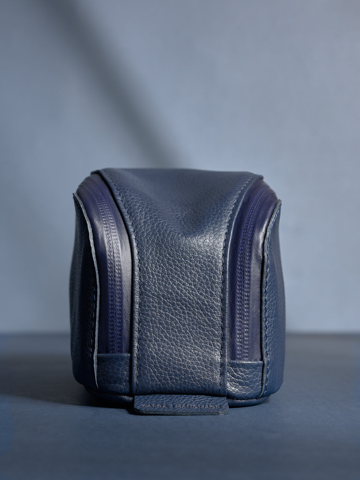 Close-up of personalized navy Capra leather toiletry bag standing upright, showing the fine grain and dual zippers.