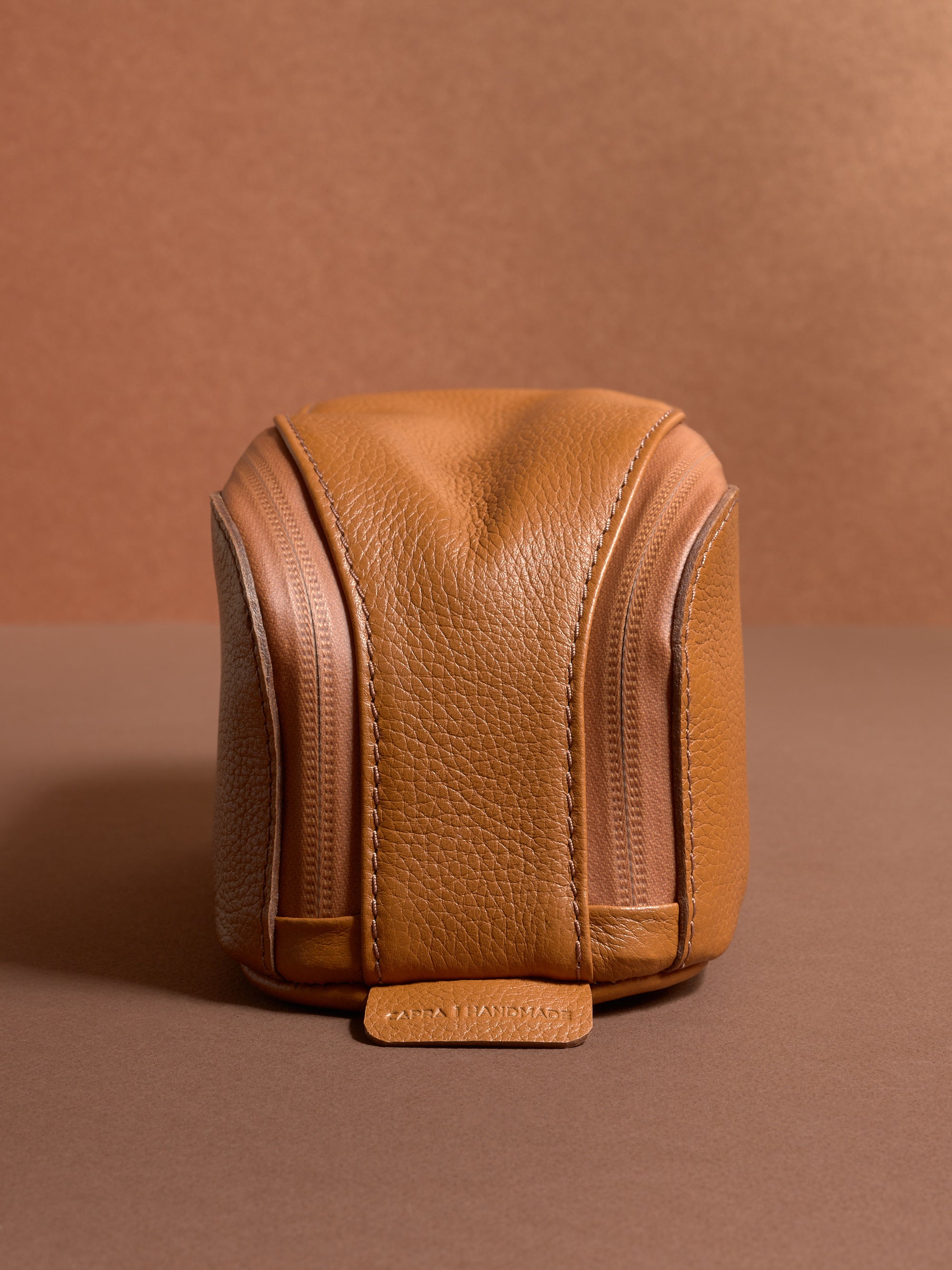 Front view of the tan Capra Leather Toiletry Bag highlighting the zipper tracks and leather tab.