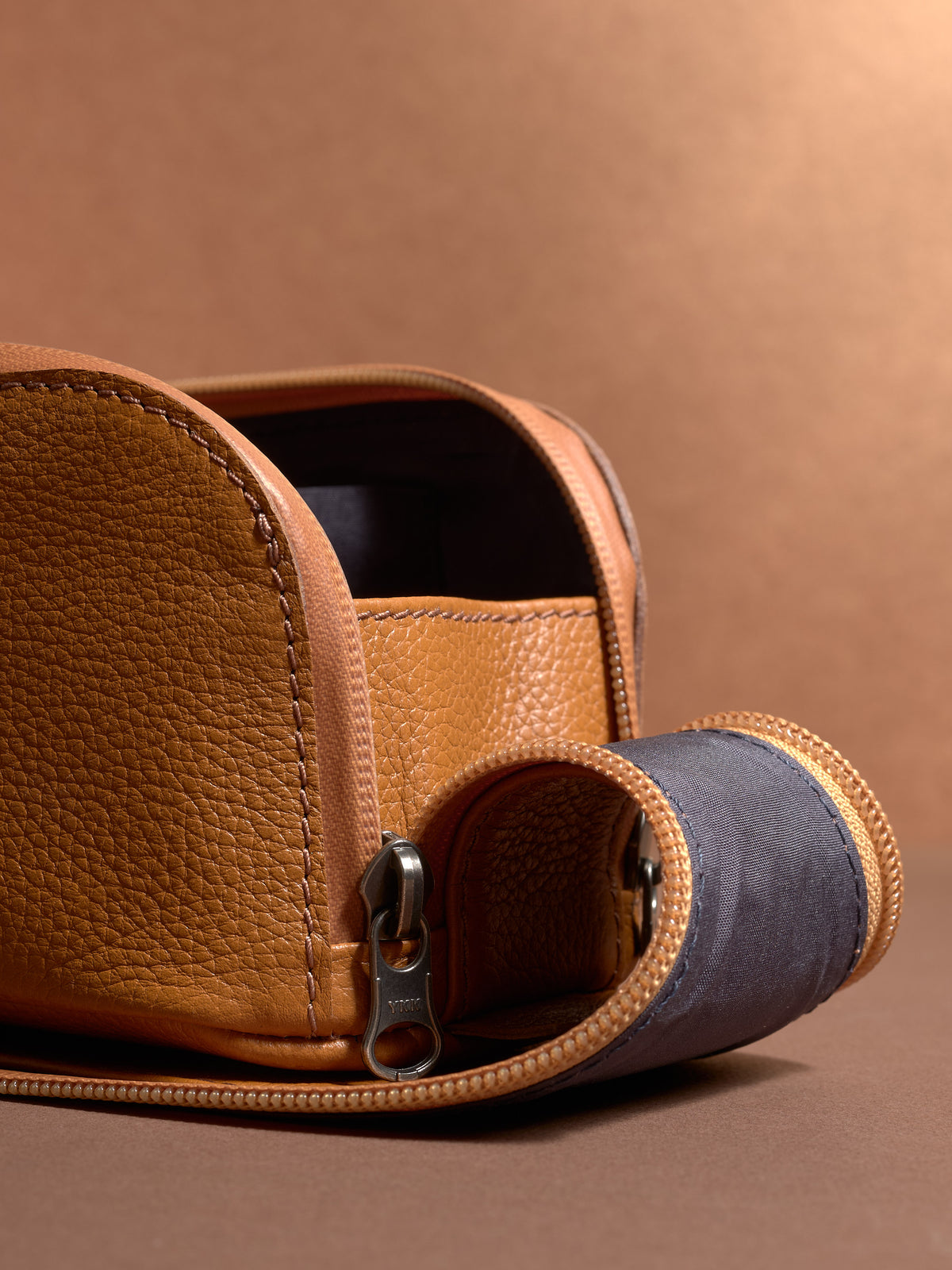 Close-up of the pebbled tan Capra Leather texture and durable zipper on the Scout Toiletry Bag.