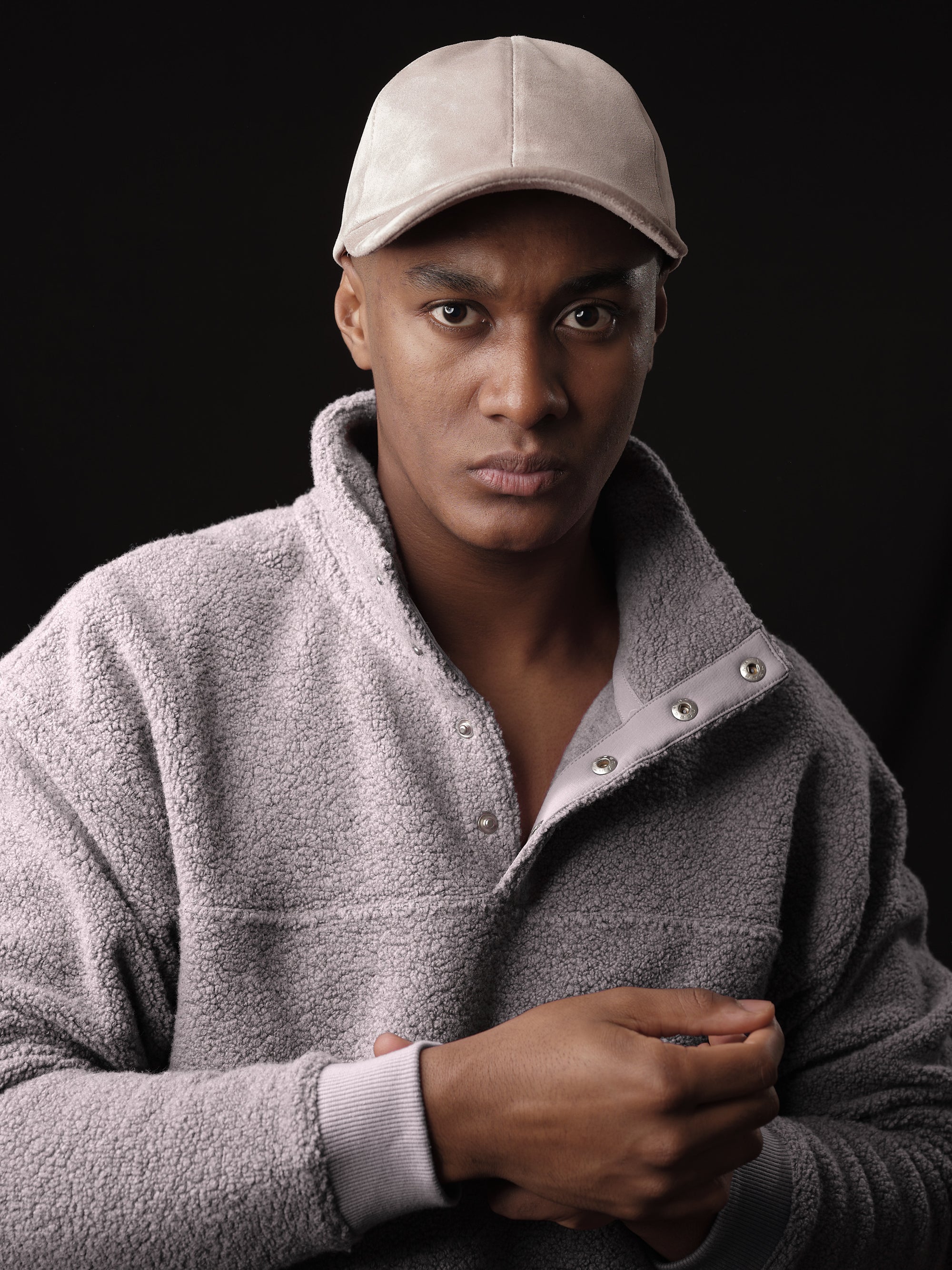 Man posing in a stylish stone suede baseball cap, handcrafted by Capra Leather