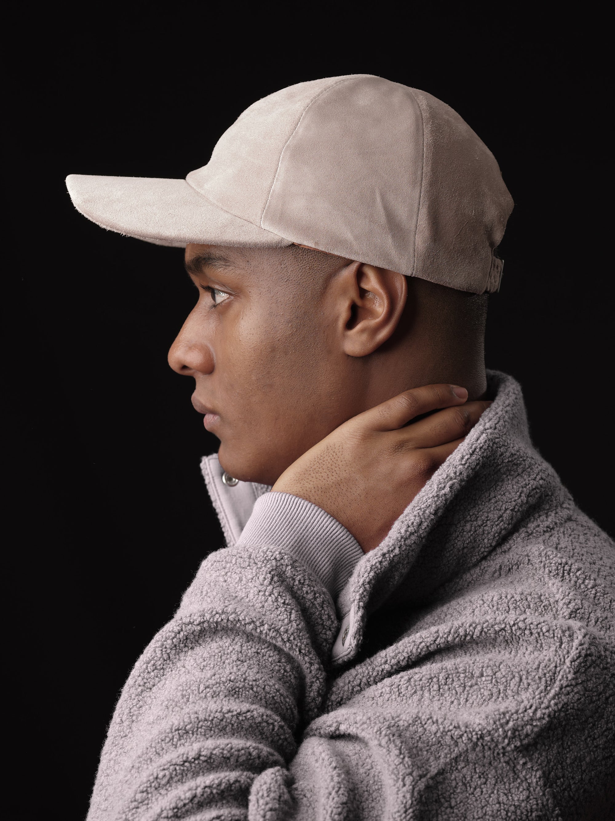 Man posing in a stylish stone suede baseball cap, handcrafted by Capra Leather