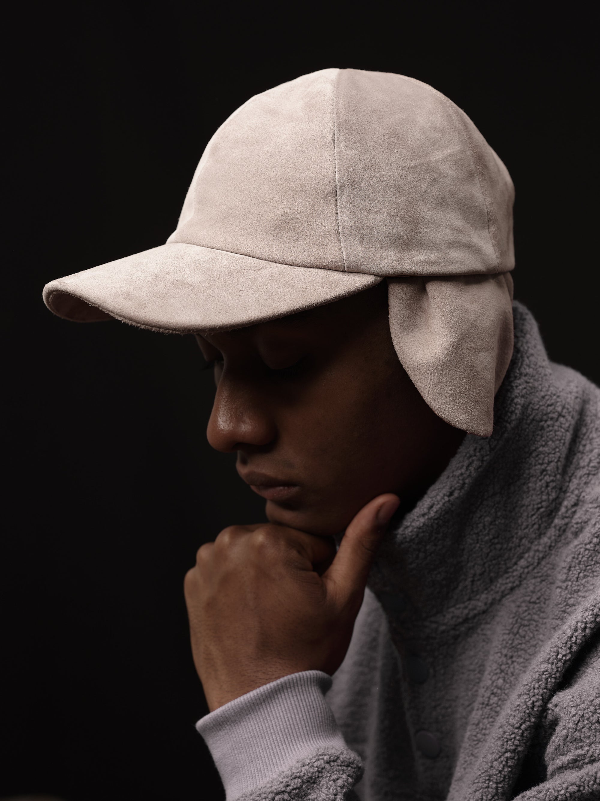 Close-up of a stone suede baseball cap with ear flaps, handcrafted by Capra Leather