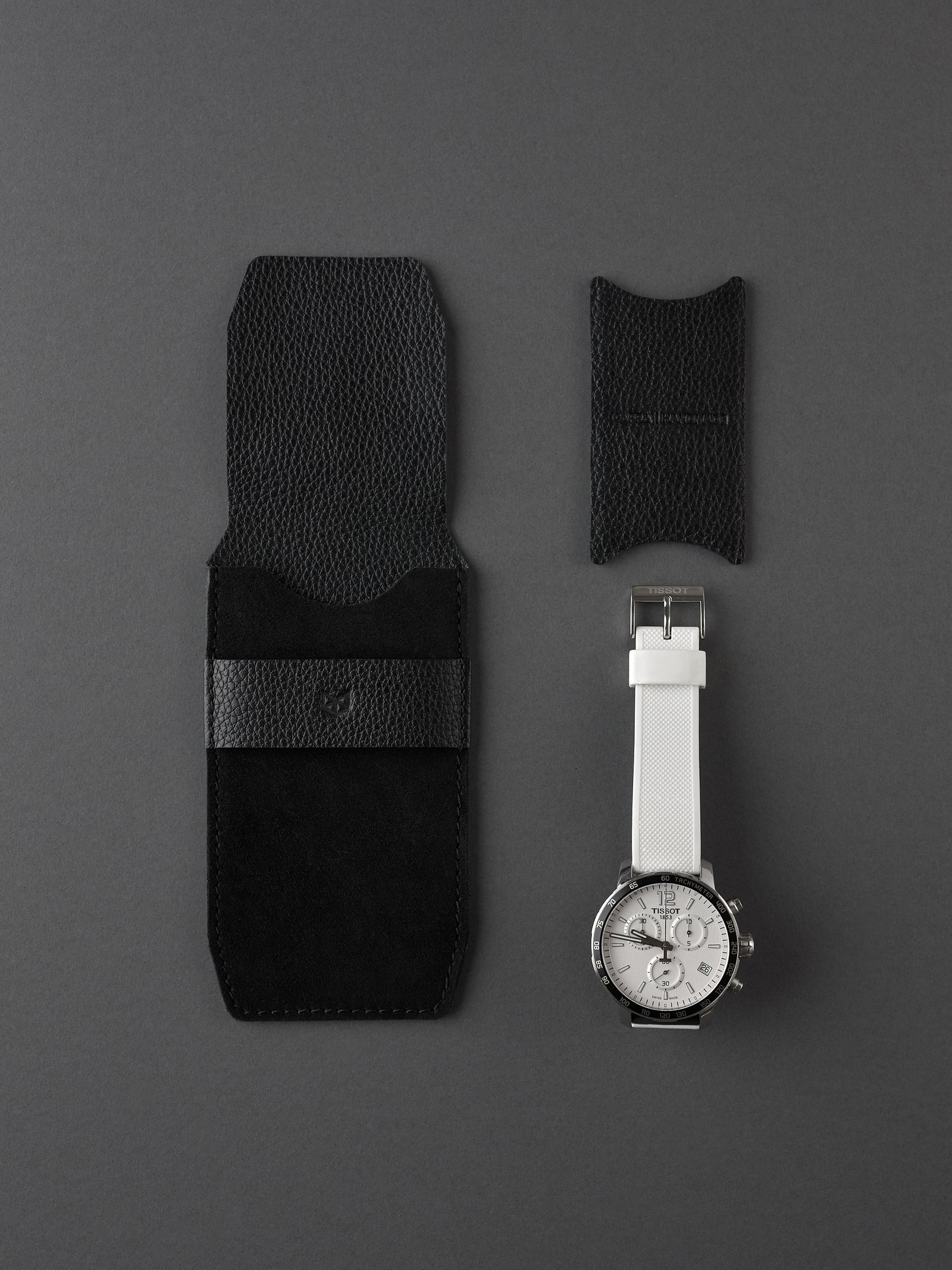 Capra Leather black suede watch pouch and small watch insert next to a men's white strap watch.