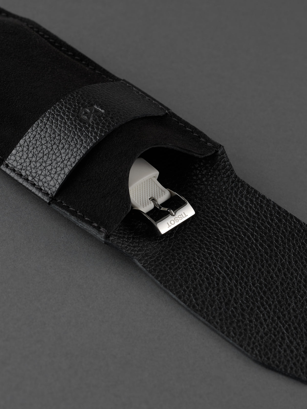 White watch strap and buckle safely stored inside a Capra Leather black suede pouch.