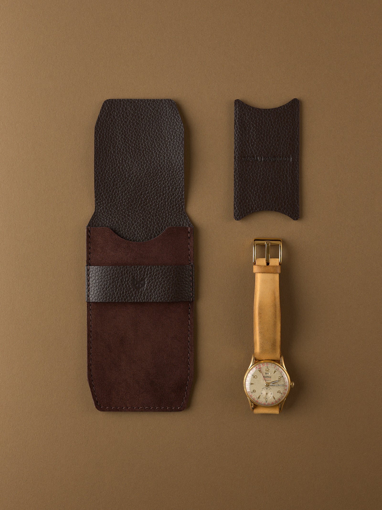 A deconstructed view of Capra Leather's brown suede watch pouch, its full-grain leather insert, and a vintage gold watch.