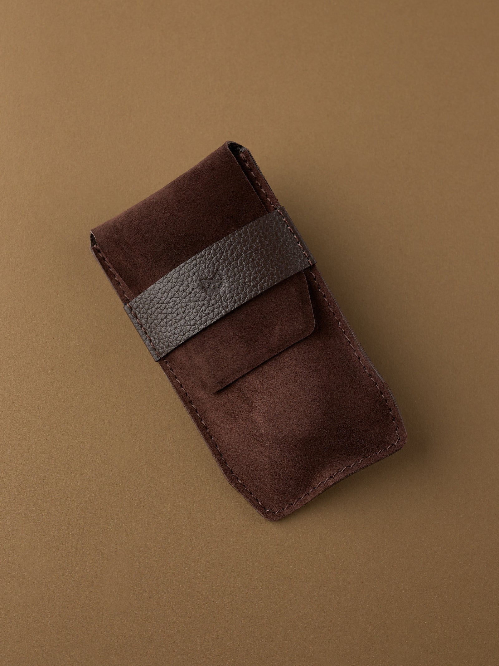 The minimalist brown Suede Watch Pouch by Capra Leather, shown closed, highlighting its rich suede and leather strap.