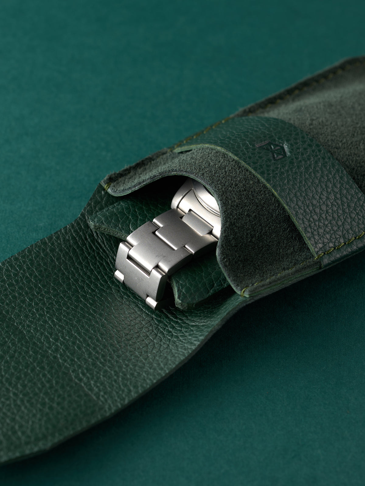 Stainless steel watch bracelet securely held inside a Capra Leather green suede pouch.
