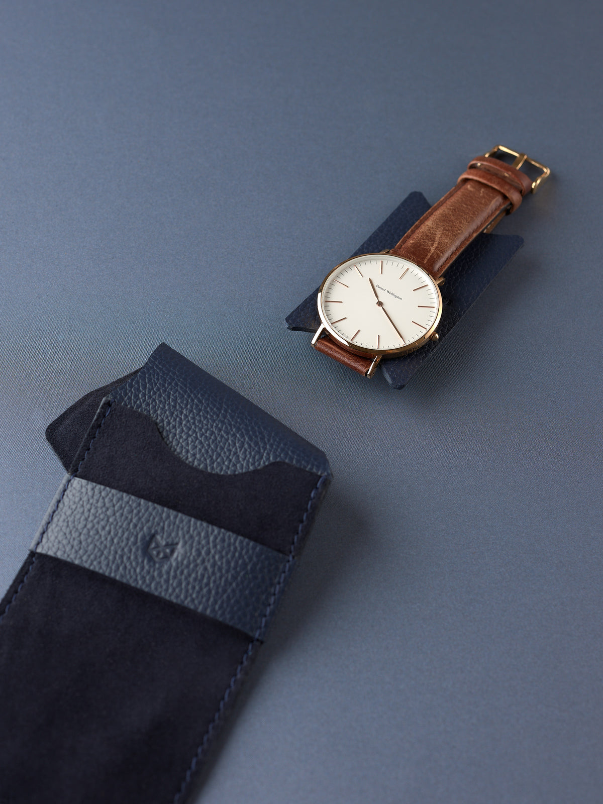 A minimalist watch rests on the navy leather insert, ready for storage inside the Capra Leather suede watch pouch.
