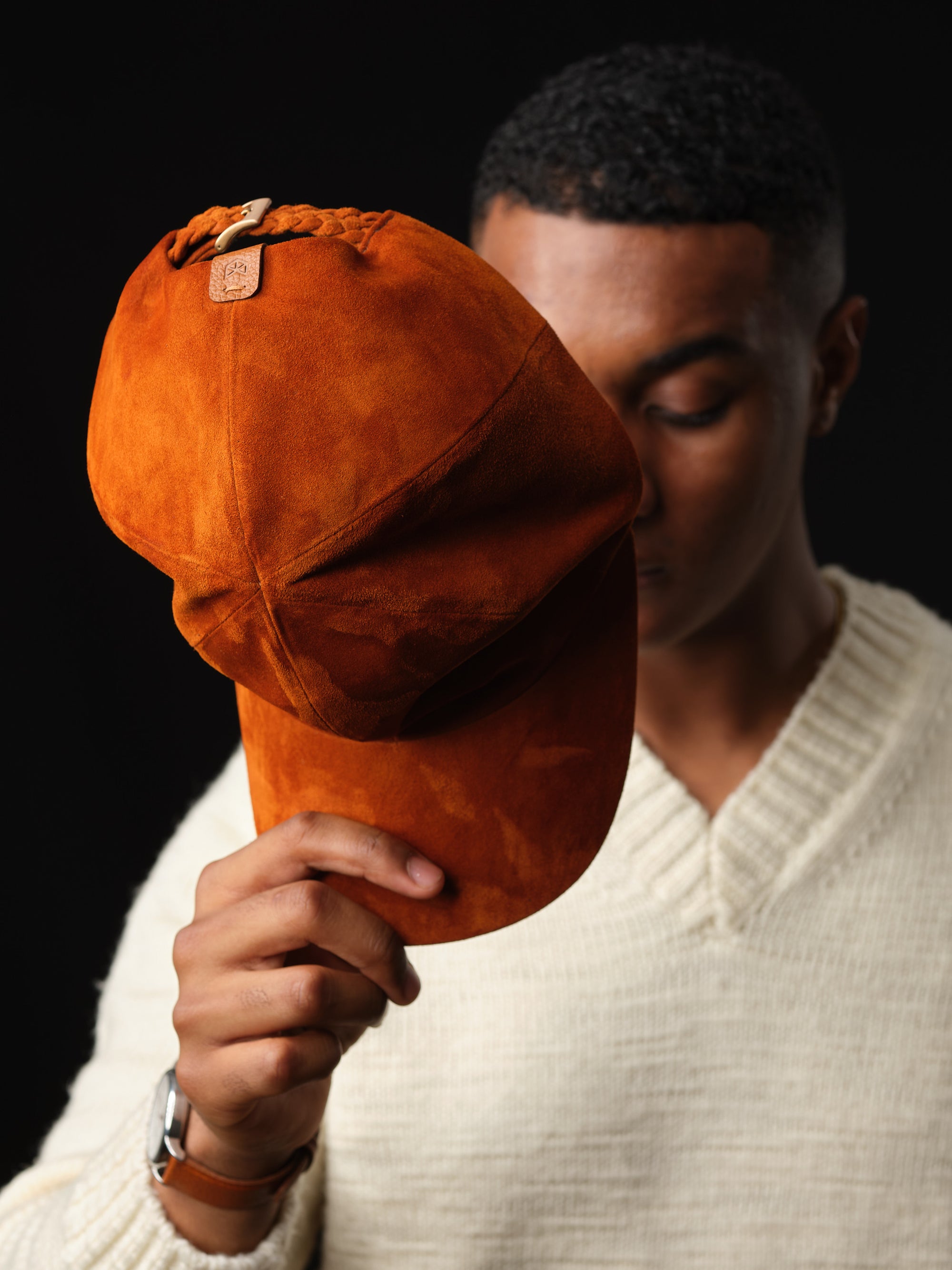 Detail of the braided strap and buckle on a tan suede baseball cap