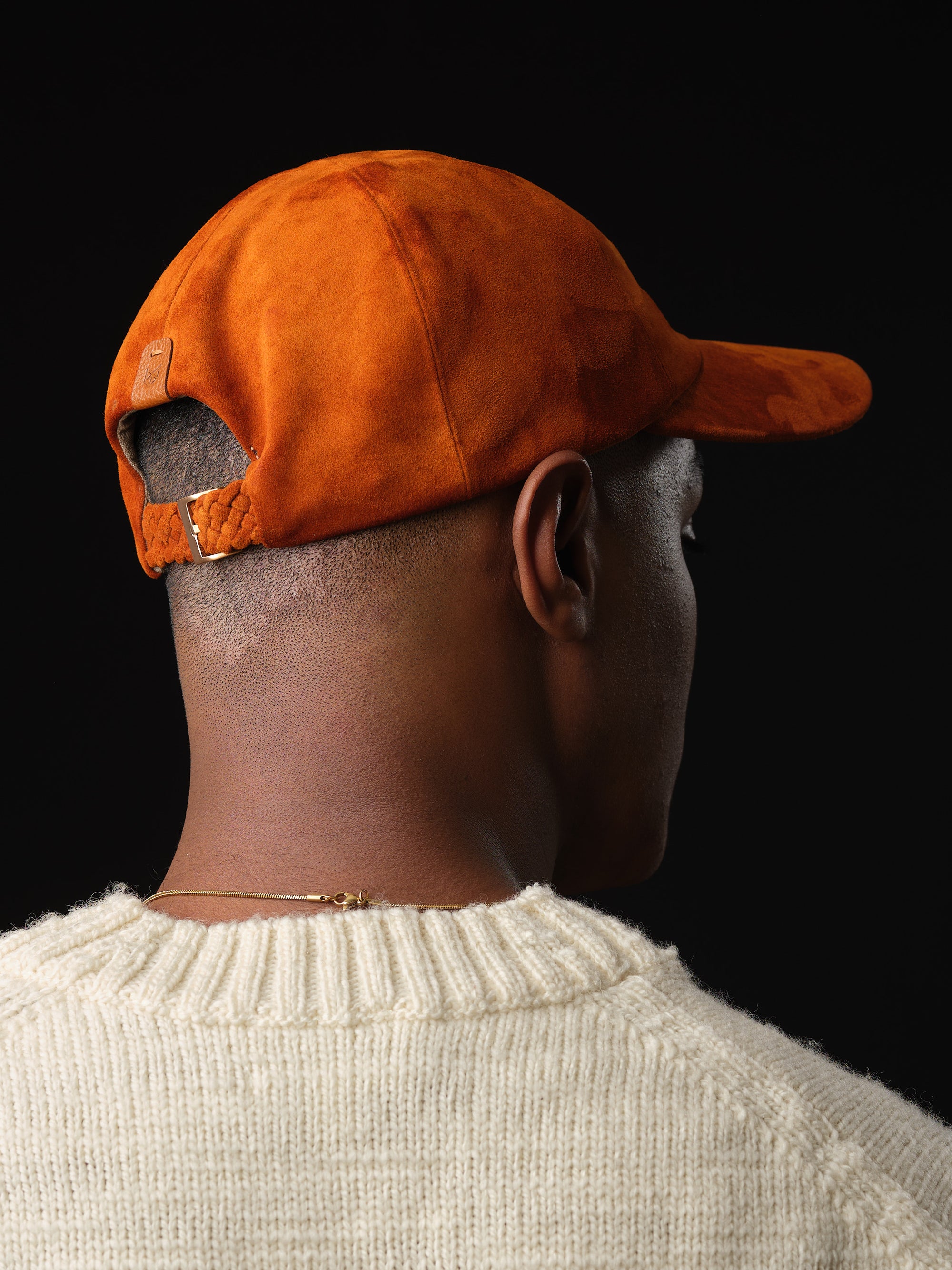 Man wearing a tan suede baseball cap, handcrafted by Capra Leather